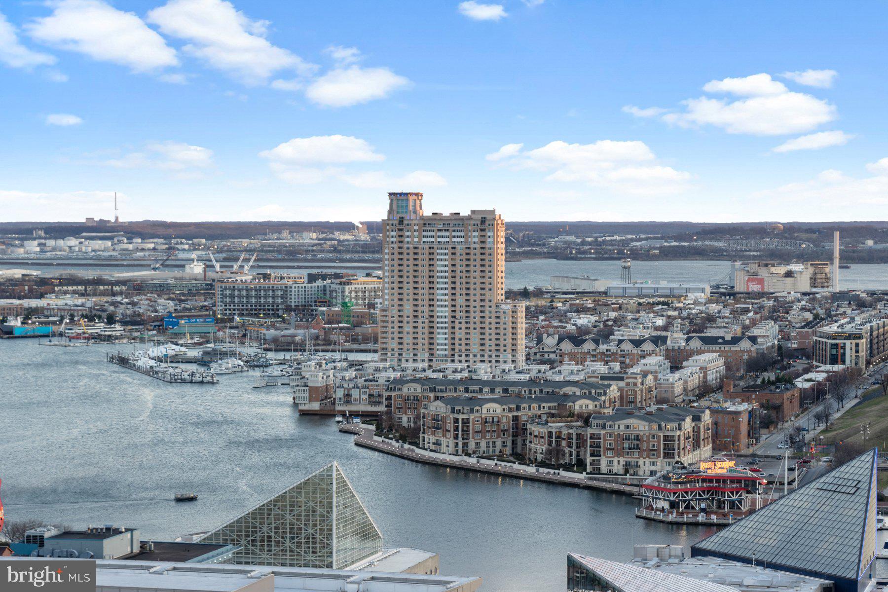 Luxury Condo living awaits you featuring a 2BR/2BA high rise unit with stunning views of the Baltimore skyline. Step into a beautifully maintained secure building, take the elevator to the 25th floor, and make your way to the door into your new home.  The open concept floor plan offers a large living room with a gas burning fireplace, a spacious dining area, and a kitchen. The kitchen features plenty of cabinets including a separate pantry cabinet, granite countertops with a complimenting tiled backsplash, and a stainless sink under a raised breakfast bar.  Down the hall is a spacious secondary bedroom, a full bath with a deep soaking tub, laundry, and a large primary bedroom featuring a walk-in closet with custom organizers, a second closet, and a private bath with a walk-in shower. Just off the kitchen is a cozy balcony offering stunning views of the surrounding city skyline.  This home is move-in ready featuring recessed lighting and gleaming hardwood floors, and is located in a building offering not one but two pools, a community room with a kitchen and bar, a gym, and so much more.  Imagine all this and in close proximity to shopping, restaurants, and commuter routes. Rare find with two parking spots and additional storage (included in monthly fee)!