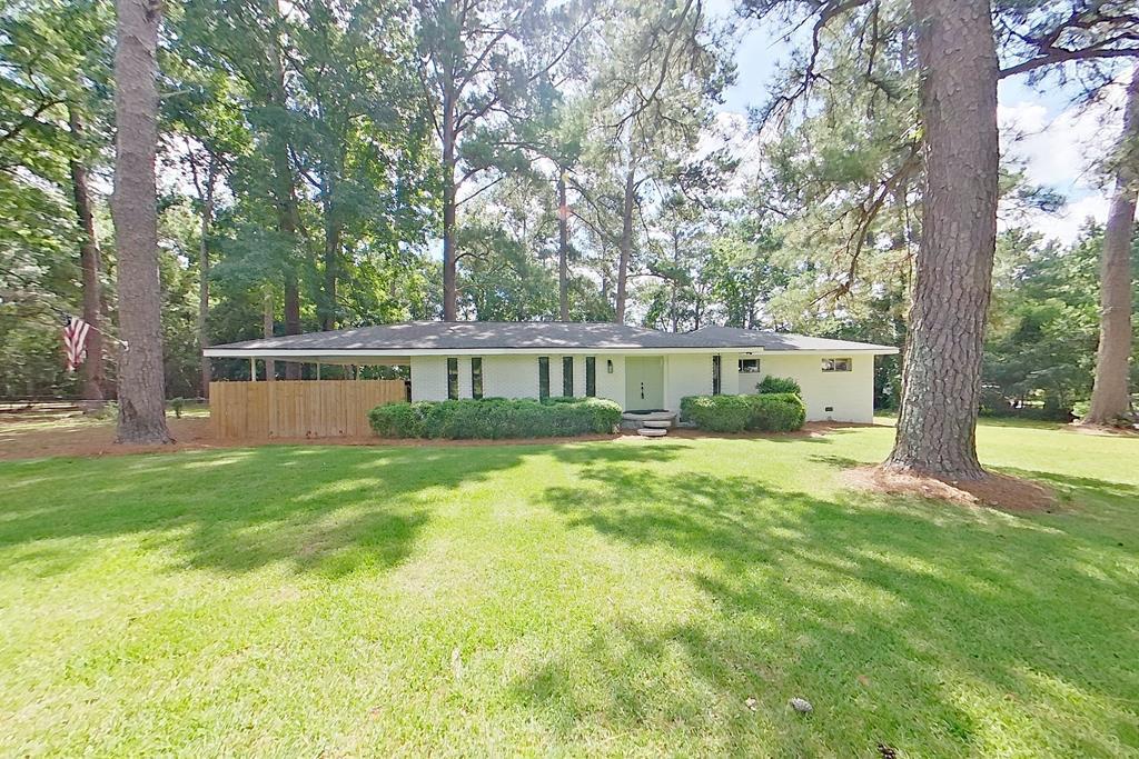 Take a step back in time with this Mid-Century Modern designed home!  Embrace the tranquility of nature while enjoying the convenience of being close to shopping, eateries, and downtown! As you approach the property, you'll be captivated by the stunning white-painted brick facade and the unique floating lily pad-inspired steps that lead you to the grand double-door entryway. Step inside and be greeted by an abundance of natural light pouring through the original mid-century column windows, highlighting the spacious and inviting living areas (2). The heart of the home is the gorgeous kitchen, equipped with sleek quartz countertops, perfect for both everyday meals and entertaining guests. Adjacent to the kitchen is a large mudroom, providing ample storage and organization space. Retreat to your tranquil master suite, complemented by two additional well-sized bedrooms. The remodeled tile bathrooms are not only stylish but also functional, ensuring every family member enjoys their own private oasis (both bathrooms have double vanities). Take advantage of the expansive fenced backyard (1 acre lot), a safe haven for family, friends, & pets alike, while you relax on the back stone patio or congregate around the fire pit-ideal for cozy gatherings under the stars! Added conveniences include a two-car carport, a basement equipped with a new sump pump, and a newer roof. The laundry room is designed for efficiency, featuring new cabinetry to keep everything tidy and organized. With wallpaper (removable) accented walls that add a touch of character and warmth to the home, this property is truly a harmonious blend of modern updates and mid-century charm!  Call to schedule your personal tour today!