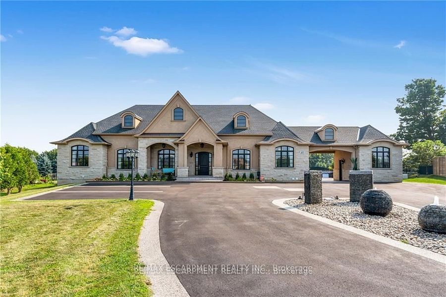 Discover the epitome of luxury at 47 Tews Lane, a sprawling bungalow on 1.85 acres in Dundas, just 7 minutes from downtown. This magnificent property boasts over 8,000 sq. ft. of living space with 14-foot ceilings, 6 bathrooms, 3 fully equipped kitchens, a theater room, and a professional-grade tennis court. Perfect for extended families, it offers separate entrances for up to three households or can be enjoyed as one grand mansion. Car enthusiasts will appreciate the oversized 4-car garage. A rare opportunity for elegant living in a prime location.