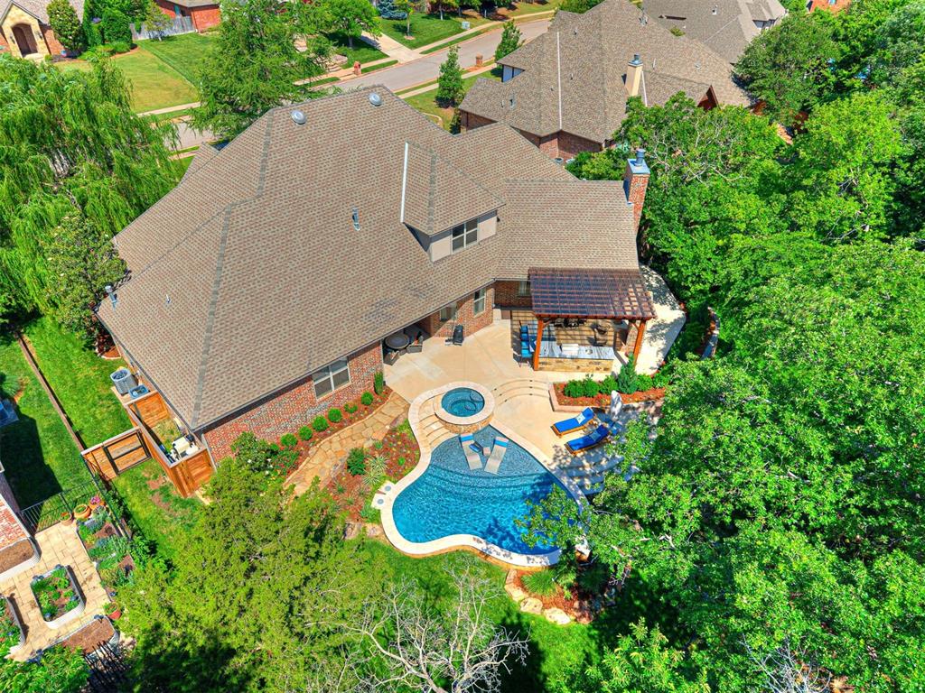 Set beneath a canopy of mature trees in Hunters Creek, this thoughtfully updated home pairs timeless architecture with refined finishes and exceptional outdoor living. The newly completed custom pool anchors a private backyard retreat with a spa, water feature, splash pad, expansive gathering areas, and a fully equipped outdoor kitchen and bar featuring a grill, refrigerator, and fireplace.Inside, the floor plan is equally suited to everyday living and entertaining. A formal living room offers flexible use, while the chef’s kitchen opens seamlessly to the main den, where a floor-to-ceiling stone fireplace creates a striking focal point. A generous pantry and walk-through coffee bar complete the kitchen.The remodeled downstairs office provides a private workspace, and the primary suite offers a serene retreat with a large bath and his-and-her closets. Three bedrooms are located on the main level, with an additional bedroom and expansive bonus room upstairs.Beautifully positioned in one of Edmond’s most established neighborhoods, this exceptional Hunters Creek property offers privacy, thoughtful design, and resort-style living near shopping, dining, and Edmond schools.
