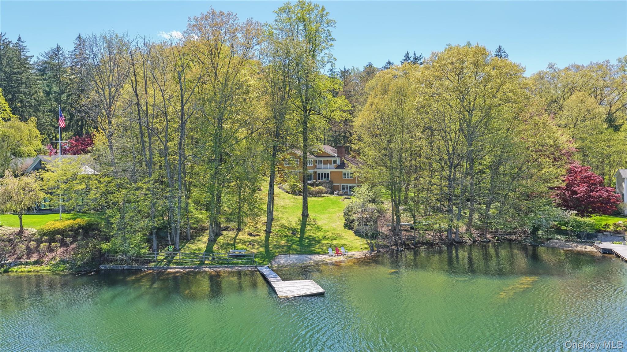 An amazing opportunity to own an epic property in Armonk’s coveted Windmill Farm community, privately set behind its own gate on 1.2 acres. This rare North Lake waterfront home offers just under 5,300 sq ft of living space and over 220 feet of shoreline on 22-acre North Lake, with a private dock for swimming, boating, and fishing, plus spectacular views from almost every room. A lovely, gently sloping lawn stretches from the house to the water’s edge, creating a serene, park-like setting.Thoughtfully custom-built with quality finishes, the home features a charming rocking chair front porch, sun-filled open spaces, and a comfortable flow ideal for both lively entertaining and everyday family living. Two stone patios overlook the lake—perfect for summer gatherings—while a beautiful balcony off the primary bedroom is an inviting spot to enjoy your morning coffee or a good book. A sandy beachfront invites you to build sandcastles, sink your toes in the warm sand, and savor the simple joys of lakefront living. From summer kayaking to winter ice-skating, every season offers a new way to enjoy this one-of-a-kind setting—just minutes to Byram Hills schools, downtown Armonk, and Metro-North, and only an hour from NYC.