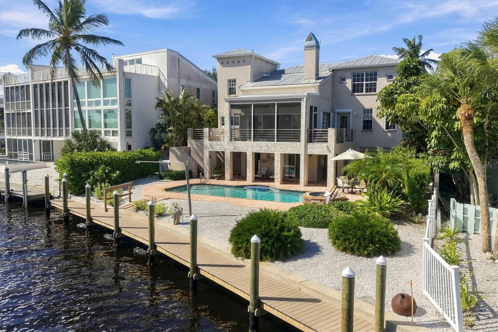 For the life you’d rather be living.  Some places ask you to keep up...this one invites you to slow down. Tucked into Boca Grande’s easygoing Dam Streets, 181 Damfino Street offers a rare opportunity to create a waterfront retreat on a coveted in-town tip lot, where long water views, exceptional boating access, and the charm of the village come together.  Here, the water sets the schedule. Head out before sunrise when the tarpon are rolling, spend an afternoon cruising to Cabbage Key or Useppa, or enjoy dinner at the Tarpon Lodge before returning home under the stars. With no bridges between your dock and the Gulf, even a tower boat or tall T-top can be part of the lifestyle. The new 2025 dock features 280 square feet of decking, water, and electric, ready to be customized to your boating needs. A dedicated tackle room keeps everything close at hand.  And when the boat stays home, the village is just as inviting. Morning coffee at the Inn Bakery, shopping along Park Avenue, and dinner at The Temptation or The Pink Elephant are all part of everyday life. Few waterfront settings offer this effortless connection between boating and village living.  Set on 0.21 acres, the property features 75 feet of sea walled frontage along a protected boat basin, a 30' x 14' pool, spa, and brick-covered patio overlooking captivating long water views. The elevated, two-story residence offers 2,507 square feet under air, four bedrooms, four baths, soaring ceilings, a fireplace, updated kitchen, and screened porch. Concrete block and stucco construction, newer roofs, updated HVAC systems, and storm panels provide a solid foundation for its next chapter. A two-car pull-through garage, separate golf cart garage, and interior spiral staircase with potential for a future elevator add versatility.  With no HOA fees and the freedom to reimagine the existing home, this is an opportunity to create something distinctly your own. A place designed around your boat, your view, and the unhurried rhythm of island life.  The location is already here. The rest is yours to create.