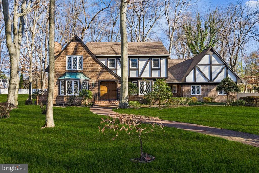 Tucked among mature trees yet set within a welcoming neighborhood, this beautifully built 5 bedroom, 3.5 bath Tudor offers the perfect balance of private, warmth, and timeless design. From the moment you arrive via the circular drive and brick walkway, you sense that this is a home made for both everyday comfort and memorable gatherings. Inside, gracious spaces unfold effortlessly. The sunken living room, with its wood-burning fireplace, rich hardwood floors, and bay window, invites quiet evenings and holiday celebrations alike. A private home office with built-ins and a pocket door offers a peaceful retreat for work or study, while the formal dining room sets the stage for family dinners and special occasions. At the heart of the home, the spacious eat-in kitchen is designed for connection. Whether it’s casual breakfasts at the island, cooking for a crowd, or lingering conversations by the bay window. Adjacent, the family room features hardwood floors, a brick-hearth fireplace, and a bay window, providing a comfortable gathering space.A large screened-in porch with grill extends the living area outdoors.The first floor also includes a laundry room with a large closet and a powder room. Heading to the second floor you will find the primary suite with a large walk-in closet, an additional closet with shelving, and a full bath.Four additional bedrooms provide excellent flexibility, including one with access from either the primary suite or the hallway, and another with an oversized bonus closet large enough to be used as an additional room. A pull-down attic is located in the hallway. The full basement is exceptionally large, with both finished and unfinished areas for recreation and storage. Step outside and discover your own backyard escape. The inground pool, brick patio, and pool house with changing room create a setting for sun-filled days, relaxed evenings, and effortless entertaining.With a brand new roof, freshly painted exterior, new HVAC, new water heater, and an oversized side-entry two-car garage, this home offers peace of mind alongside enduring charm. A rare opportunity to enjoy space, privacy, and classic Tudor character, this is a home meant to be lived in, loved, and shared. Although there are no known issues, this home and pool are being conveyed in “as is” condition.