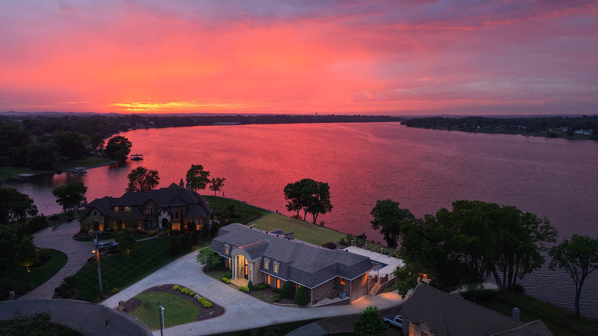 Imagine relaxing by the pool watching the sun set over the lake after spending the day on the water...this home has it all! LAKEFRONT HOME WITH PRIVATE BOAT RAMP! That's correct, 1 of only 3 private boat ramps on the lake. In addition to the 2 car garage & 2 car carport there is an additional 2 car tandem garage perfectly located with direct access to the private boat ramp. Perfect for storing your boat, jet ski, pool & lake toys, etc. BUILD YOUR DREAM BOAT DOCK! Property has been approved by the Corps of Engineers for new owner to build a dock & power at the shoreline is already installed. This home has all the space you could ever need. Over 9,000 sqft of living & entertaining space as well as a huge covered porch & outdoor kitchen by the pool. Huge dining room that could be used as a sitting room, smaller dining area with built in cabinets, an eat-in kitchen with amazing views. Enormous open main living area off the kitchen with floor to ceiling doors that slide open for inside/outside living all overlooking the pool & lake. 4 bedrooms on the main level, 1 dedicated bedroom upstairs & flexible space to use other areas as bonus/play rooms, offices or additional bedrooms if needed. HUGE dressing room/closet upstairs right off the elevator. Basement level is a great space with a wet bar & changing rooms/shower for the pool. Would be a great spot for a sauna as well. So much to say about this home but so little space to say it. You must come out & see it for yourself. Make sure to check out the video!