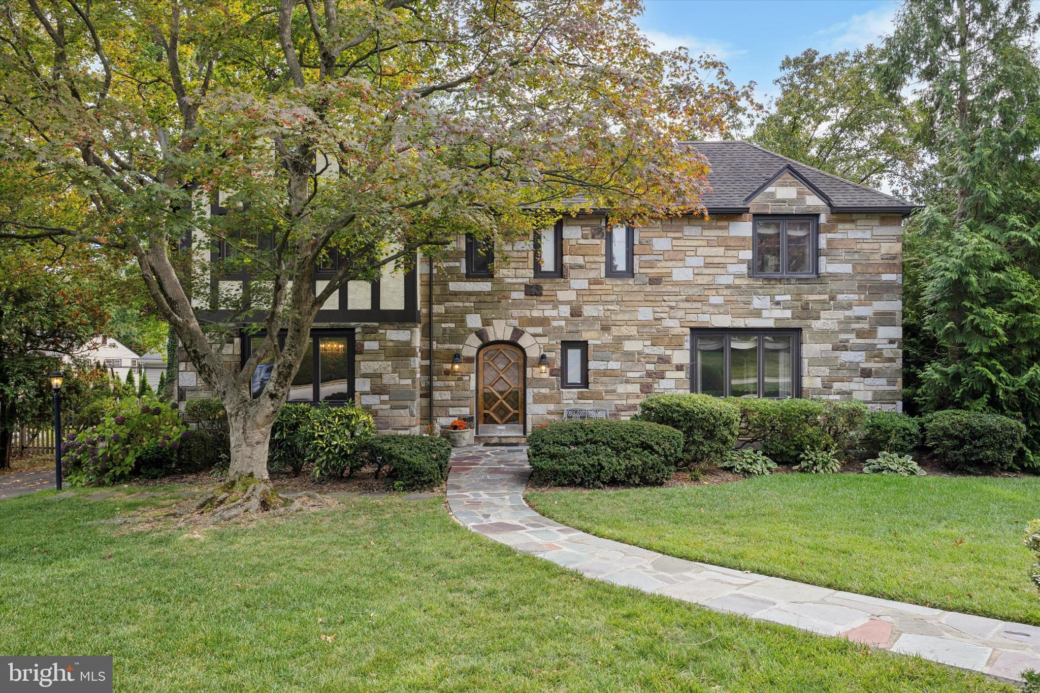 Welcome to 1354 Drayton Lane, a beautiful and meticulously maintained stone Tudor residence nestled on a quiet, tree-lined street in the award-winning Lower Merion School District.  This home offers thoughtful design, premium finishes and abundant light, space and storage across every level.  Its versatile spaces are perfect for family living, entertaining or working from home.  Approaching the home via its lovely front yard and slate walkway, you enter through a beautiful center hall foyer flanked by a finished powder room and large coat closet. The foyer offers a seamless flow between the generous first-floor spaces - living room, dining room, den, sunroom and kitchen.  These rooms showcase hardwood oak flooring, recessed lighting, crown molding, custom-built mahogany bookshelves, cabinetry and French doors. Additional architectural features include an abundance of windows, including two large bay windows and walls of windows in the sunroom, all of which fill the home with warmth, natural sunlight and beautiful views of the plush outdoor landscape. The eat-in kitchen, which features Wood-Mode cabinetry and granite countertops, has direct access to a large, secluded backyard oasis.  With trees, mature plantings, a stone patio, and a dedicated gas line for grilling, enjoy this beautifully landscaped yard for relaxation, play and gardening.On the second floor, at the top of the stairs you will find a sizeable landing that sets the tone of the second floor which has four large corner bedrooms and three full bathrooms. The primary suite is set apart for privacy and includes two spacious closets, a dressing area, and an updated ceramic tiled bathroom. Each of the other three bedrooms has multiple windows and newly installed hardwood flooring. One of these additional bedrooms also includes an ensuite bathroom and another stands out for its extensive closet space and system. These generous secondary bedrooms are easily adaptable to your needs – for family members, guests or creative use of space for work or hobbies. The upstairs hallway also includes a full bathroom, linen closet, cedar closet and built-in bookshelves.In addition to the living space on the first and second floors, this home boasts over 1,000+ square feet of space on other levels for storage and other uses. Bessler stairs from the upstairs hallway provide access to a floored attic, which contains not only open space but also a finished closet for storing seasonal clothing. The lower level includes a large recreation/playroom space, a separate laundry area with a full-length wall of storage cabinets with shelving, and an unfinished area that includes a door leading to your private driveway.This exceptional property offers elegance, great space, and an unbeatable location.   Move in and enjoy this home - ideally situated in a great neighborhood, walking distance from parks, the library, top-rated schools, houses of worship, and public transportation, with easy access to shopping, businesses and a convenient commute to Center City.