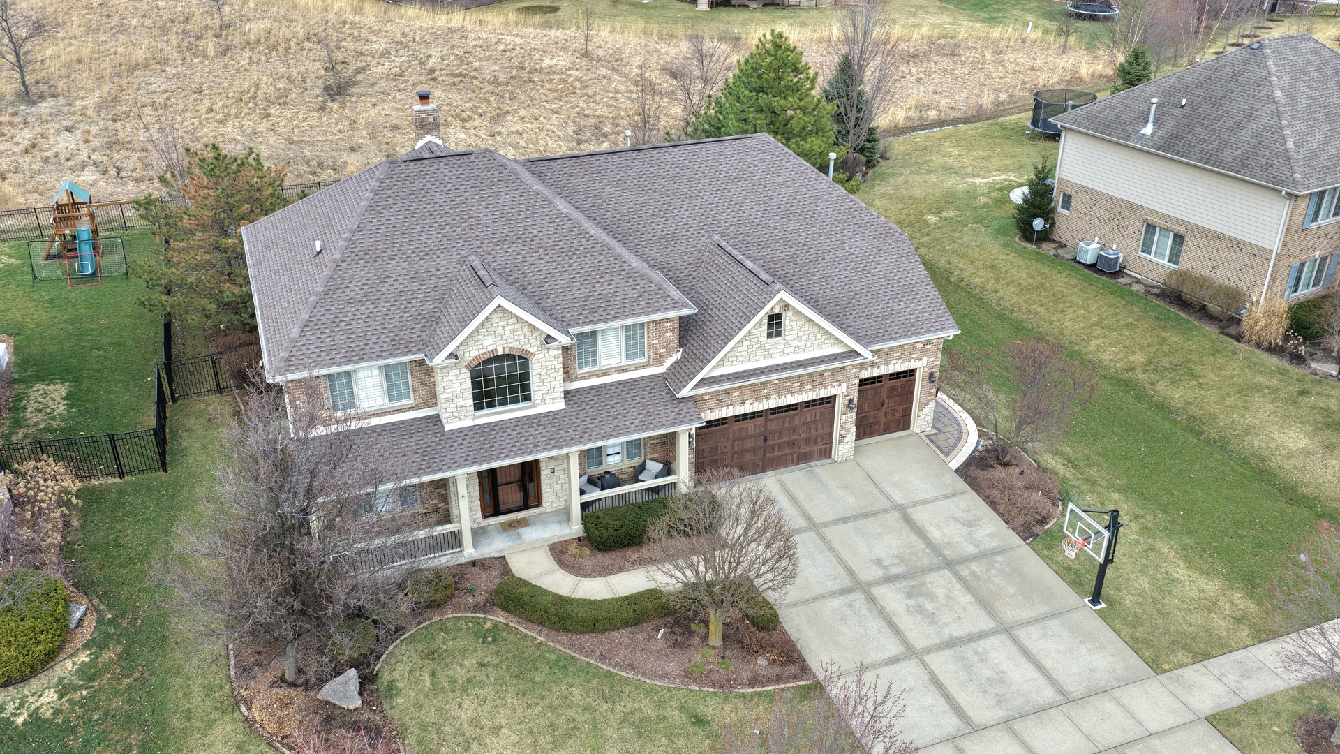 Welcome to this stunning two-story home in the highly sought-after Boulder Ridge community, where thoughtful upgrades, elegant finishes, and exceptional outdoor living combine to create a truly special property. From the moment you enter, you'll notice the attention to detail throughout the main level, highlighted by rich Brazilian hardwood floors, oversized white trim, and plantation shutter window treatments that add both style and warmth. The formal living and dining rooms feature classic wainscoting, creating a refined space ideal for hosting gatherings and holiday dinners. The spacious family room centers around a beautiful stone gas fireplace, offering the perfect place to relax or entertain. The updated kitchen is designed for both beauty and function with granite countertops, stainless steel appliances, a tile backsplash, custom cabinetry, and a large island with breakfast bar seating, along with a cooktop and range hood, double oven, oversized Kenmore Elite refrigerator, and pantry cupboard for generous storage. The main level also offers a versatile fifth bedroom or office along with a full bathroom, providing flexibility for guests, work-from-home needs, or more. Upstairs you'll find four large bedrooms and the convenience of a second-floor laundry room. The spacious master suite features a vaulted ceiling and private sitting area, creating a relaxing retreat, while the luxurious primary bath includes double sinks, a whirlpool tub, separate shower, private water closet, and a large walk-in closet. The finished basement adds even more living space with a large recreation room, exercise room, storage rooms, and a wet bar with granite countertops and wine refrigerators, plus a half bath with plumbing roughed in for a future shower. The three-car garage features custom cabinets and durable epoxy flooring, and the roof, garage door, and garage door opener were all replaced just five years ago. Outside, the fenced backyard offers professional landscaping, a large stamped concrete patio, and an incredible in-ground pool installed in 2021 with an auto cover, diving board, slide, and decorative deck and fountain jets, along with a fire pit and outdoor bar with pergola that create the perfect space for relaxing or entertaining.