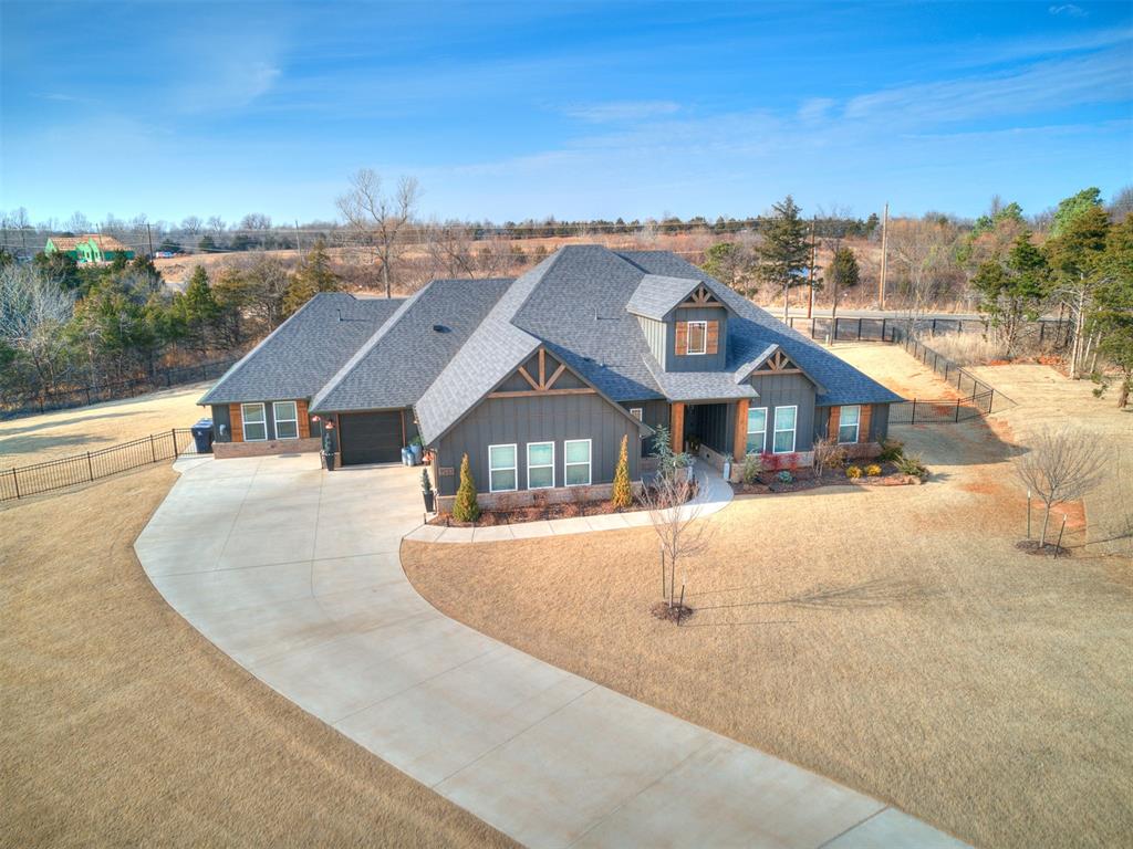 An exceptional modern craftsman styled home sitting on nearly one acre, offering a wooded view, w/ refined design, thoughtful upgrades, and meticulous care throughout.Only two years old, this one is definitely  better than new.  From the soaring ceilings, wood flooring, and dramatic stone fireplace to the real wood shutters and elevated lighting selections, every detail reflects intentional design and pride of ownership.  An amazing floor plan boasts 5 bedrooms, and a large media/flex room, all on one level, spaced out for privacy.  The open living spaces transition seamlessly to an expansive covered patio outfitted with electric screens, and a fire pit, creating a sophisticated indoor-outdoor experience ideal for year-round entertaining.  Plenty of room for a pool, the fully fenced and  sodded grounds feature complete irrigation and hardwired pathway lighting, for both beauty and function. An expanded driveway and oversized garage with epoxy flooring provide generous space for vehicles and storage, while the built-in storm shelter adds peace of mind. The home also includes a tankless water heater, generator wiring with gas run, and pre-wired for a future shop, with pad in place.This was a custom home, and offers a lot of upgrades, fencing, etc. the new ones don't have, for about the same price per sq. ft.   It truly is amazing.