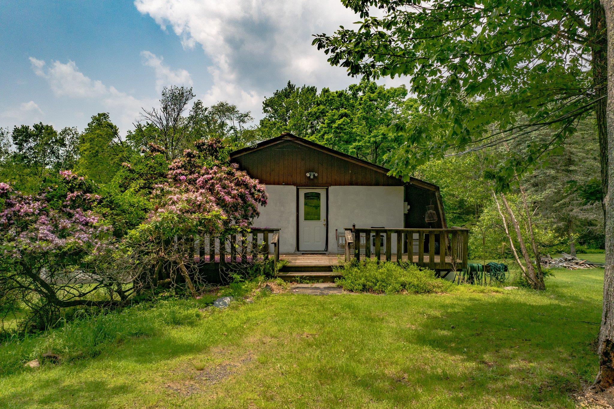 View of front facade featuring a front yard and a wooden deck