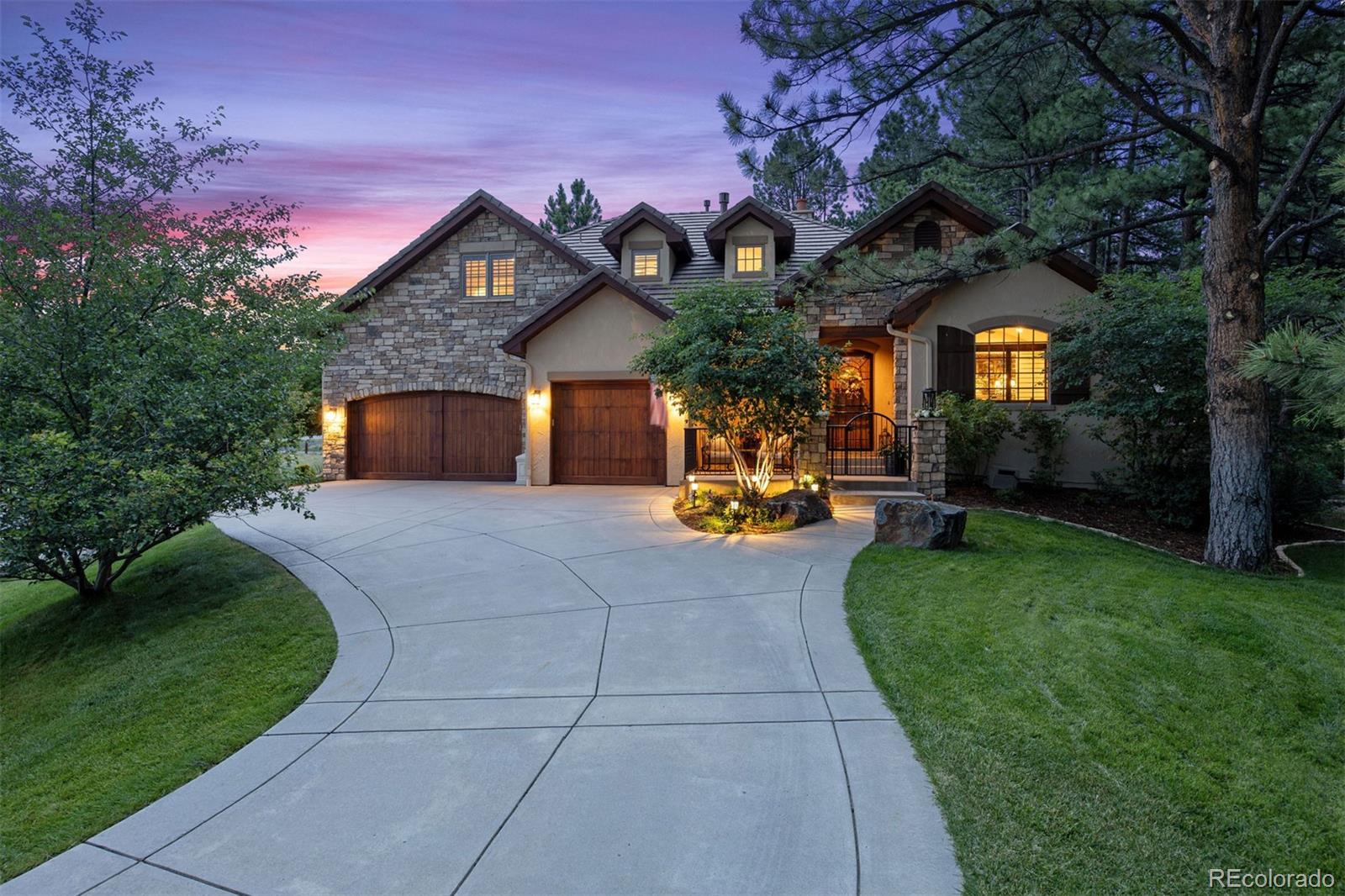 In the exclusive Red Pass enclave of the Village Lake area within The Village at Castle Pines, a distinguished, fine luxury home offers no-maintenance living with a main-floor primary suite. Views over 13 acres of open meadow, and shade from 29 mature pines create a beautiful setting. A remodel touches nearly everything, from a brand-new kitchen to a dreamy primary bath. The back private patio showcases a stacked stone gas fireplace and a quiet water feature spilling into a small pond.An iron gate with stone columns create a courtyard at the entry. A two-story foyer opens overhead, curved staircase, lighted art nooks, and a crystal chandelier catching light from every angle. Polished, natural 6-inch plank hickory floors stretch across the main level. The great room's carved travertine fireplace and soaring ceiling carry the scale outward to a kitchen that opens onto it all. Jenn-Air appliances, a gas cooktop with griddle, convection ovens, and a 10-foot island complete the space, with a walk-in pantry and butler's bar handling the overflow, and a corner nook catching morning light. The main floor primary suite has its own wing. The bath is sparkling and bright, with dual vanities, a freestanding soaking tub beneath a crystal chandelier, and a glass-enclosed walk-in shower finished in decorative tile. The walk-in closet, custom by Closets by Design, connects to the laundry room. Downstairs, the finished basement is its own destination: a wet bar with quartz counters, a glass-door wine cellar, and a recreation room set the scene for game nights, warmed by a second fireplace. Upstairs, two bedroom suites and a loft overlooking the great room give the house room to breathe. Minutes from the renovated Village Lake Fitness Center, offering a heated lap pool, spa, and cardio and weight training. Castle Pines Village is home to 2 private 18-hole golf courses. Finished throughout with the fine detail touches a discerning buyer will recognize.