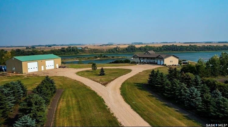 Spectacular Riverfront Acreage – 10 Acres on the South Saskatchewan River
This meticulously maintained 10-acre property offers an extraordinary lifestyle, perched above the banks of the South Saskatchewan River with breathtaking panoramic views from every angle. Surrounded by natural and planted trees, the setting is both private and picturesque, with a tree-lined driveway welcoming you home.
The beautifully designed 1,460 sq. ft. bungalow features 4 bedrooms and 3 bathrooms, blending comfort with elegance. The heart of the home is the open-concept hickory kitchen, equipped with ample cabinetry, a central island, and seamless flow into the dining and living rooms—all enhanced by soaring vaulted ceilings and expansive windows to capture the stunning scenery.
Step onto the full-width back deck—accessible from both the dining area and the master bedroom—to enjoy unobstructed river views and endless skies. A large farmhouse-style mudroom/laundry room connects directly to the attached garage for added convenience.
Downstairs, flared stairs lead to a spacious walk-out basement with a cozy family room featuring a wood-burning stove and access to a covered patio. The lower level also includes a games room, two additional bedrooms, a home office, a full bathroom, and extensive storage—including a separate garage entrance.
For hobbyists or entrepreneurs, the 68’ x 40’ dream workshop is a standout feature. Half is fully heated, complete with a bathroom and mezzanine level, while the other half offers cold storage. Whether you’re working, building, or relaxing—this is the ultimate man cave.
Geothermal heating and cooling service both the home and shop, offering energy efficiency and year-round comfort. City water is on site, and holding tanks are conveniently located in the shop.
This is a truly rare offering—acreage, views, privacy, and top-quality infrastructure all in one. Properties like this don’t come along every day.
