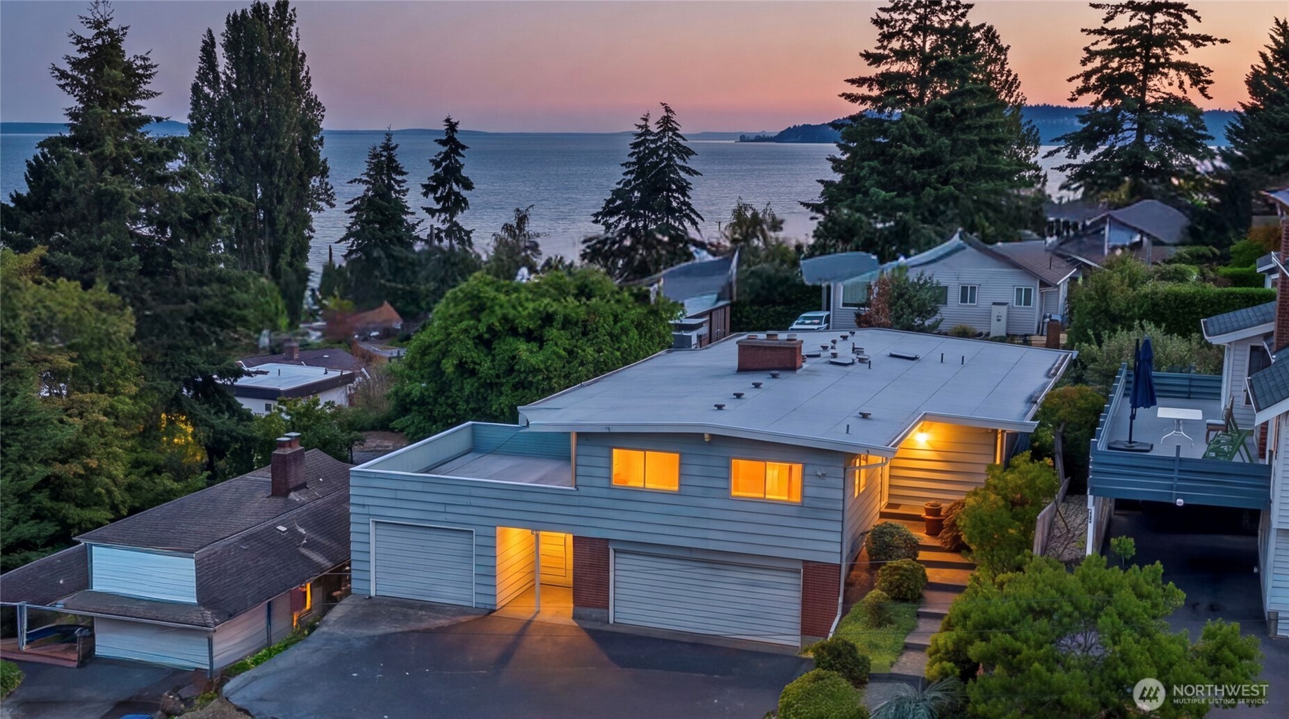 Perched above Three Tree Point this sprawling Mid-Century home features 180 degree views of Sound, Mountains and Islands. Come home to stunning PNW living. Enjoy tea on the patio shaded by towering trees or drinks on your deck while watching ships sail off through the sunset. This hidden gem of a community dates back to the days before the road when Seattle's elite would travel by boat to their summer retreats along Puget Sound. Walking distance to beach access, community events, and a cafe in the original general store.    Unique layout and multiple utility boxes allow for conversion to three separate living spaces. North wing of home features a separate entrance, two bedrooms, bath off primary bedroom and a large bathtub in a common area that was previously an additional kitchen. Basement also features a separate entrance along with a bedroom, fireplace lounge, two unfinished work spaces and a separate cooking space with oven, range and sink.