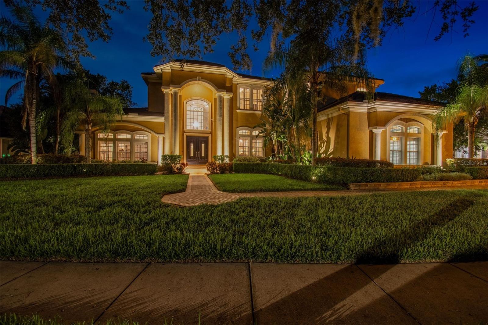 Under contract-accepting backup offers. TAMPA PALMS LUXURY – A RESIDENCE OF GRANDEUR & COMFORT
Welcome to an extraordinary estate tucked inside the highly sought-after community of Tampa Palms, where elegance meets everyday comfort. Spanning over 5,200 square feet, this stunning five-bedroom, four full and two half bath home is designed for those who appreciate both refined living and effortless entertaining.

From the moment you enter, the grand ceilings and expansive light-filled spaces create a sense of sophistication. At the heart of the home, the **chef-inspired kitchen—featured in Florida Home Magazine—**showcases a beveled-edge oversized island and custom-lit display cabinetry that blend striking design with flawless functionality.

The layout flows seamlessly into living and dining areas, perfect for hosting unforgettable gatherings or enjoying quiet evenings with family. Step outside to your private poolside oasis, where mature landscaping and a serene water view provide the perfect backdrop for relaxation. Equipped with a stunning outdoor kitchen, multiple inviting seating areas, and a serene poolside waterfall.

The home’s thoughtfully designed floor plan includes a signature wine collection room, ideal for connoisseurs and entertainers alike. Each of the five spacious bedrooms offers a private retreat, with the luxurious primary suite boasting spa-inspired finishes and abundant natural light.

Additional highlights include: Access to the exclusive Tampa Palms Clubhouse, offering resort-style amenities, beautifully curated outdoor spaces with mature trees and lush landscaping and ample storage and workshop area for your lifestyle needs.

Whether you’re envisioning lively poolside gatherings, savoring wine from your collection, or enjoying a tranquil morning by the water, this home delivers a lifestyle that is both elevated and inviting. Experience Tampa Palms living at its finest.