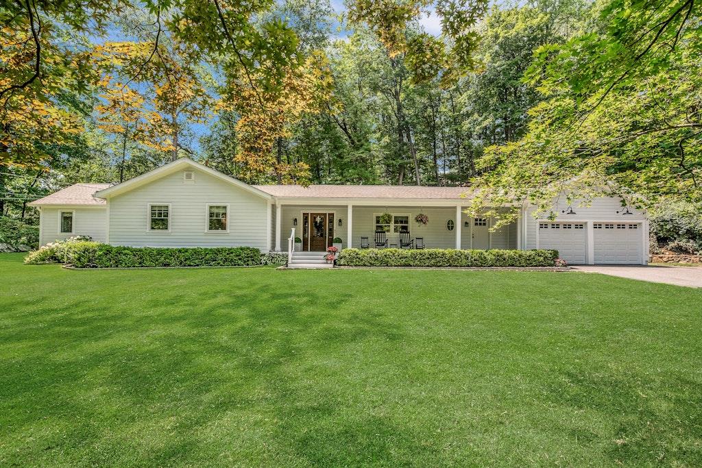 Beautifully remodeled Ranch-style home on a private, level property just a short walk to downtown Armonk, NY. A covered front porch with durable Trex decking welcomes you into a bright open layout, thoughtfully designed with hardwood floors, crown molding, custom trim, and recessed lighting throughout. The main living area includes a dining and living room with an electric fireplace and opens to a Trex deck, while the family room opens to a stone patio wired and ready for outdoor TV entertainment. The modern eat-in kitchen is outfitted with quartz countertops, stainless steel appliances, a butler pantry, in addition to a powder room, and a laundry area. The primary suite includes a dressing area with a built-in vanity and a luxurious en-suite bath with heated floors and a heated towel rack. Two additional bedrooms share a beautifully renovated full bath, also with heated floors and a towel rack. Notable upgrades include new windows and doors, central air conditioning, connected to natural gas, Nest thermostats, and a whole-house PFAS water treatment system. A full basement offers ample storage or potential future living space. Approved building plans and rendering for future home addition are available.