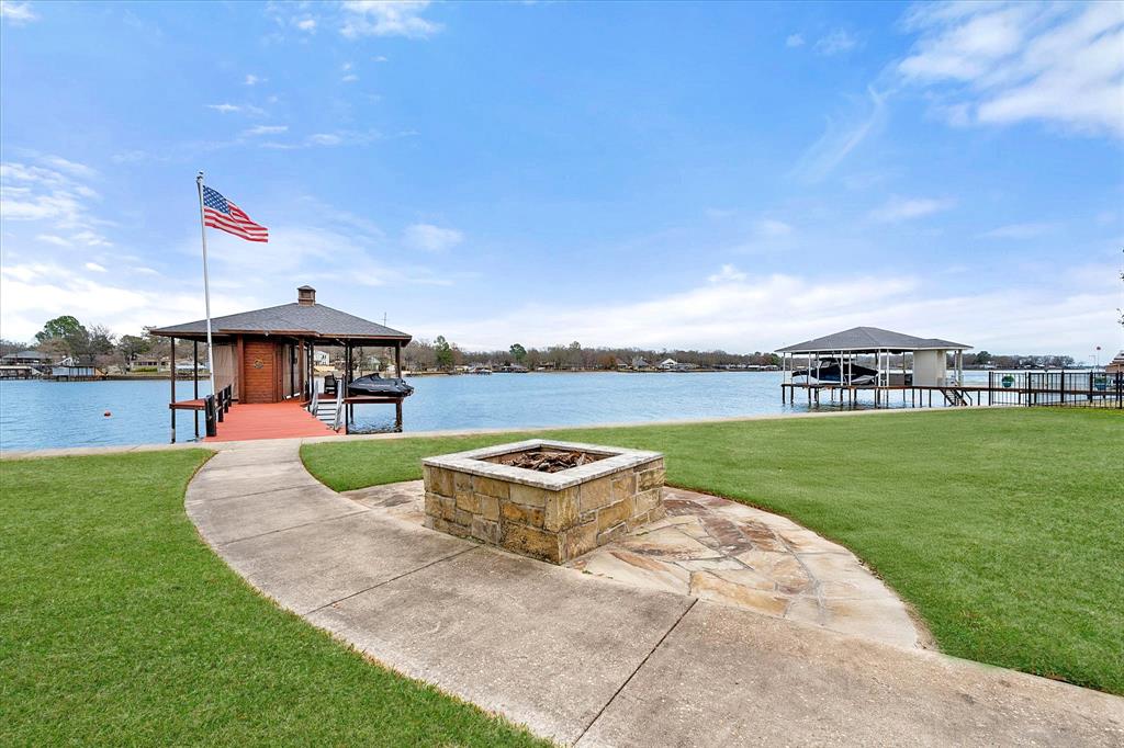 Wake up to lake life in this charming waterfront home located in Enchanted Oaks on Cedar Creek Lake. Move in ready and will be sold fully furnished. Designed for both everyday living and entertaining, the home features a large living room centered around a cozy stone fireplace—perfect for gathering with family and friends. Multiple dining areas offer flexibility for casual meals or hosting special occasions. Bunk room is great for the kids or overflow guest space. The screened-in back porch is an ideal spot to unwind in comfort while enjoying the tranquility. The property continues to impress with a boathouse that offers covered space for your boat and jet skis featuring a touchless electric boat cover, along with a generously sized deck—perfect for fishing, relaxing, or enjoying your morning coffee by the lake. A partially fenced backyard adds functionality while maintaining open views of the water. Whether you’re looking for a full-time residence or a weekend retreat, this waterfront home offers the lifestyle you’ve been dreaming of on Cedar Creek Lake.Subdivision is city & has city tax in lieu of HOA dues & includes trash, plus has pool, playground, soccer field, fire station & hydrants, 2 boat launches & piers avail to residents.WOW Features include: Totally remodeled-- New roof, gutted inside new wiring and spray foam insulation. Completed February 2019. New retaining wall January 2026, Sprinkler system, Electric touchless boat cover. Will be sold fully furnished inside and out and include: 2018 Ferris Hydro mower, 2 - 2019 Yamaha UX Cruiser Jet Skis. Optional for additional price: 2015 Crown Line 255 SS Boat with 2015 EZ Loader Trailer -55K Low hours serviced for 2026 season