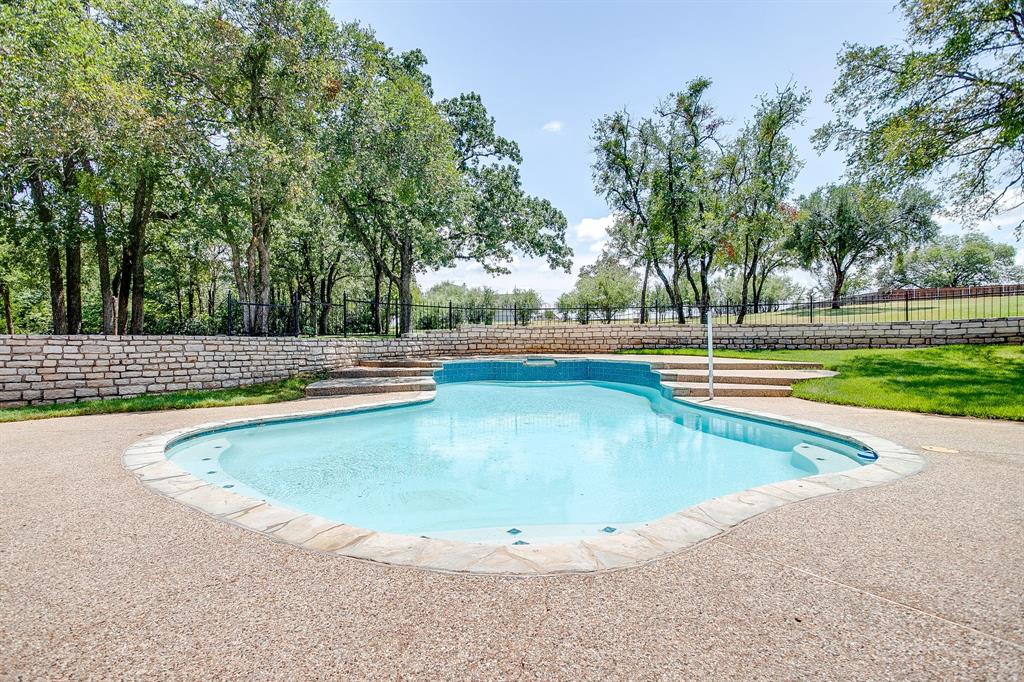 Discover the perfect blend of comfort, functionality, and recreation at this stunning property on 1.78 acres in sought-after Granbury. With 4 bedrooms, 2.5 baths, and a spacious upstairs bonus or game room, this home offers versatile living for families of all sizes. The inviting floor plan features a living room with a cozy fireplace and expansive windows overlooking the backyard oasis. A beautifully updated kitchen includes stainless steel appliances, a center island, and abundant storage. The private primary suite boasts a spa-inspired bath with a soaking tub, walk-in shower, and dual vanities. Step outside to enjoy a sparkling saltwater pool with attached spa, perfect for entertaining or relaxing under the Texas sun. Mature trees and open green space create both shade and privacy, while the oversized patio provides plenty of room for gatherings. Craftsmen, car enthusiasts, hobbyists, or business owners will appreciate the 25x20 brick workshop or detached garage with water, electric, heating, and a bathroom. The property also includes a 40x35 RV pad with full hookups for water, electric, and sewer was also designed to double as a future workshop site. A private water well supplies the irrigation system, keeping the landscape lush and low-maintenance. Additional highlights include a 3-car attached garage, an expansive driveway with extra parking, and convenient access to shopping, dining, schools, and Lake Granbury. This property truly has it all — a beautiful home, a backyard retreat, and space to fit every lifestyle need.