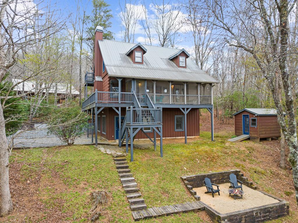 Private Wooded Retreat | 150' Lake Laurel Frontage + Toccoa River Access | Furnished Cabin + 2-Story Barn. Tucked at the end of a quiet cul-de-sac and surrounded by mature woods, this fully furnished mountain retreat delivers instant comfort and long-term value. Thoughtfully designed with rustic log furnishings, the home sleeps up to 10 and features stainless steel appliances, a wood-burning fireplace with gas log starter, and updated mechanical systems—completely move-in ready from day one. Step outside and the setting truly shines. With 150 feet of private pond frontage on Lake Laurel, you'll enjoy peaceful water views, excellent fishing, and total seclusion. The community also offers access to the Toccoa River, adding even more opportunity for outdoor recreation. Whether it's morning coffee by the water or evenings by the fire, this property is built for year-round enjoyment. A standout feature is the impressive 48x32 two-story barn. Fully stick-built and equipped with its own water, septic, and a full tile bath, it offers incredible flexibility—ideal for guest quarters, a workshop, studio, or future expansion. Located in a no short-term rental community, this property offers a rare level of peace, privacy, and true neighborhood connection—surrounded by long-term owners who value quiet mountain living. Two fully equipped structures, water frontage, river access, and turnkey convenience—properties like this are increasingly hard to find.