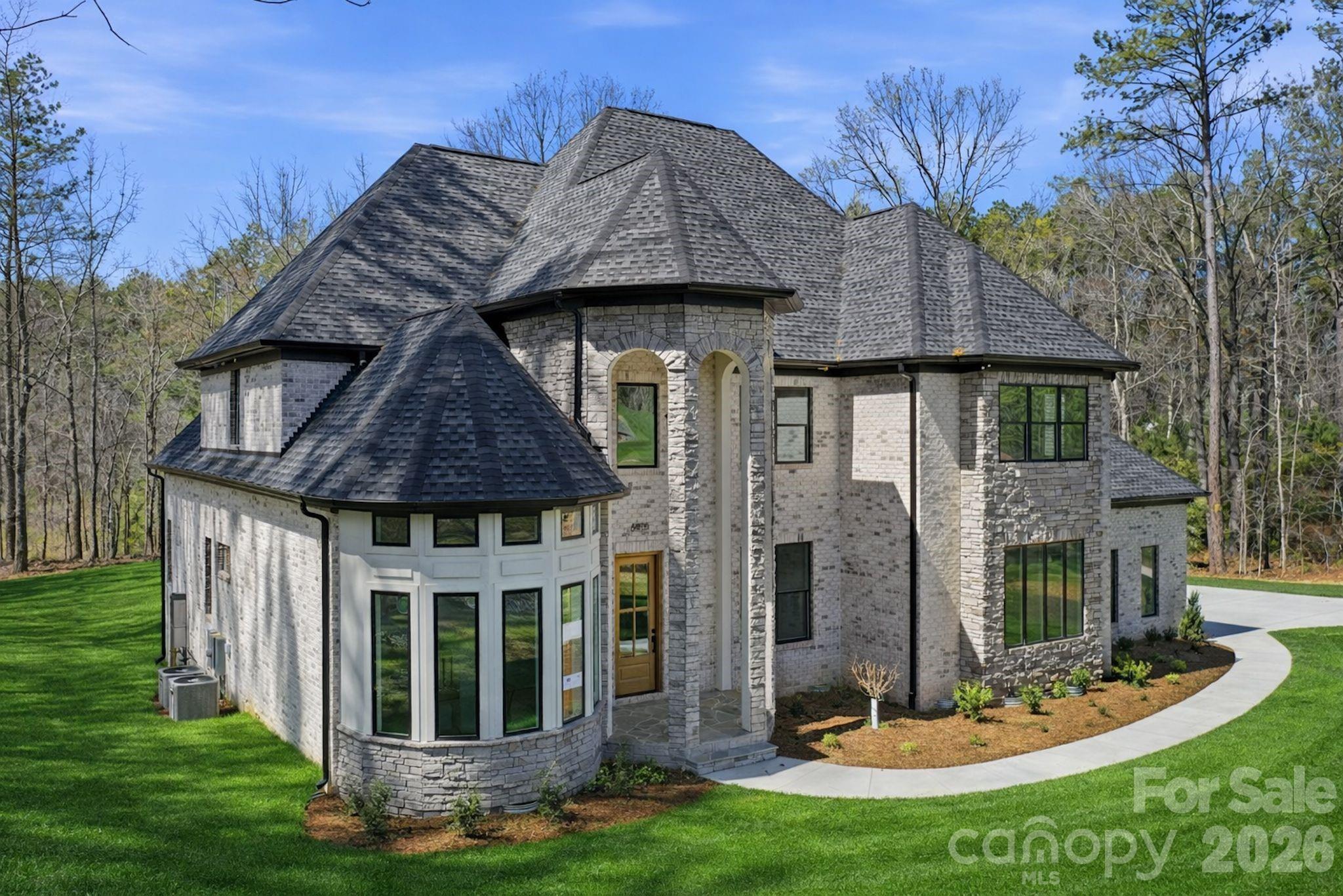 Discover exceptional privacy and timeless elegance at **6405 Chimney Bluff**, beautifully situated on a wooded 1.759-acre corner homesite in the gated community of Riverchase Estates.Offering 3,867 square feet of thoughtfully designed living space, this custom-built residence features 4 bedrooms, 4 full bathrooms, 1 half bath, and a spacious 3-car garage. Its striking stone exterior, dramatic rooflines, and welcoming entrance create an impressive first impression.Inside, a stunning two-story great room welcomes you with soaring ceilings, abundant natural light, and a beautiful fireplace. The gourmet kitchen features premium GE Monogram appliances, custom cabinetry, and an oversized island, creating a wonderful space for everyday living and entertaining.The main-level primary suite offers a peaceful retreat with cathedral ceilings, beautiful windows, and tranquil wooded views. A second main-level ensuite provides exceptional flexibility for guests or multigenerational living, while a dedicated office offers a comfortable and private workspace.Upstairs, two additional ensuite bedrooms offer privacy and comfort. A large bonus/media room with an entertainment bar, beverage refrigerator, and convenient half bath provides an inviting space for movie nights, recreation, or entertaining. Directly accessible from the bonus room is an expansive, full walk-in storage area, offering exceptional convenience without the need for pull-down attic stairs.Outdoor living is equally inviting. Enjoy quiet mornings or evenings by the fireplace on the screened porch overlooking the wooded, pool-ready backyard. With nearly 1.76 acres, there is ample room to create your own outdoor retreat while enjoying the beauty and privacy of the natural surroundings.Riverchase Estates offers an impressive collection of amenities, including a beautifully appointed clubhouse, resort-style pool, fitness center, sports courts, playground, gathering spaces, and scenic walking trails leading toward the Catawba River.**A distinctive residence where thoughtful design, beautiful surroundings, and the lifestyle of Riverchase Estates come together. **