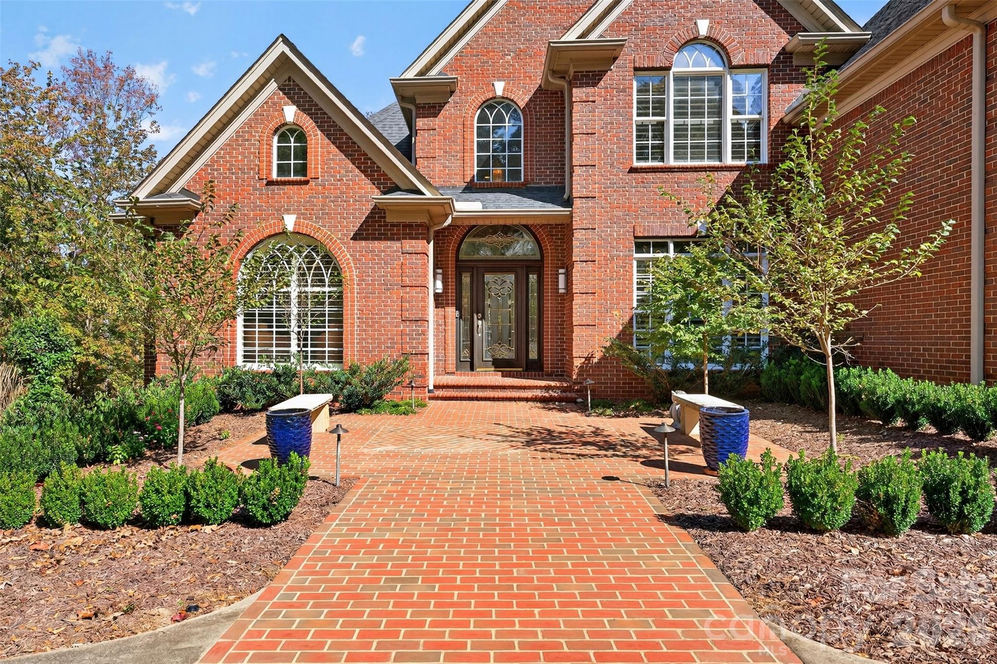 WOW will be the first words spoken when entering this luxurious home. You have a private HOME GYM, private HOME THEATER, private POOL and 2nd LIVING QUARTERS! What else could one ask for? A quaint English garden greets your guests as they pull into the circular drive. Inside the front door find soaring cathedral ceilings and a creamy neutral white color spanning the walls. To the left of the entrance, is a cozy library/office with grand bookcases, a warm fireplace, and to your right, a modern, pristine dining room with elegant lighting fixtures to drool over. The great room, with its coffered ceiling, is a focal point of the house and includes a wall of windows overlooking the pool and yard, and a 2nd fireplace for chilly nights. There is a chef's dream kitchen with new quartz countertops and quartz backsplash, an industrial 6-burner high-end GE Monogram gas range, double ovens and warm wood cabinets make cooking a joy! The primary bedroom is on the main level and has marble countertops in the ensuite with shower, tub and walk-in closet. Upstairs boasts an additional 3 large bedrooms and a sunny playroom. On the terrace level, which could be used as second living quarters, you have a kitchenette, home gym, home theater, full bath, a 3rd entertaining space and large storage room/ workshop with a garage door entry for golf carts, pool and lawn equipment.  The entire home is adorned with elegant plantation shutters and the back lawn is fenced and has gorgeous perennials to be enjoyed year after year.  Carolina Country Club is a guard gated sought after community offering nature trails and so much more.  Golf, pickleball, tennis, athletic facilities, dining and pool memberships are available.