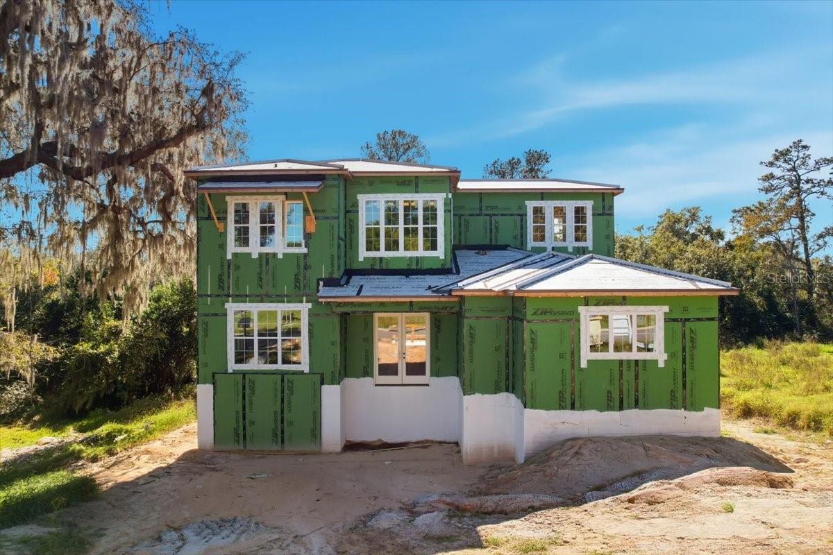 Under Construction. WALK-OUT Basement home with all the Custom Finishes! Talbot Custom Homes brings you this tri-level home with a 3 car garage and mother-in law suite, renowned for their energy-efficient and high-quality construction in Central Florida. Located in the gated Sanctuary Golf Estates, this 3-level masterpiece offers an incredible 4,400 square feet of air-conditioned living space (5,684 total under roof) and sits on a serene .29-acre lot with conservation tree views. ACT NOW and still choose your finishes & design selections! This home stands out as one of the most unique properties in Florida, boasting a rare walk-out basement. Built into the hillside with durable poured concrete walls, the basement features a 1-bedroom, 1-bathroom multi-generational suite, complete with kitchen plumbing and a private living space—ideal for extended family or guests. This level also includes a spacious 3-car garage, ensuring plenty of room for vehicles and storage. On the main level, you’ll find a light-filled, open-concept living area with designer details throughout. The kitchen showcases quartz countertops, a huge walk in pantry, high-end cabinetry, and luxury appliances, all seamlessly tied together with a modern aesthetic. The white oak engineered hardwood flooring adds warmth and elegance, while the living space flows out to a cantilevered deck overlooking your private nature preserve, with a dedicated staircase to get down to the lower level from the deck. The primary suite is a sanctuary in itself, featuring expansive windows, a large walk-in closet, and a contemporary spa-like bathroom. This floor also includes a dedicated office space, ideal for work-from-home professionals. The upper level offers even more space for your family with 2 additional bedrooms, and a versatile loft. Altogether, this home includes 5 bedrooms, 4 and 2 half bathrooms, an office, and a loft, providing the perfect blend of luxury and functionality. Talbot Custom Homes & their professional design team has spared no expense in delivering superior finishes and attention to detail, with some that you can still customize to your taste—choose your finishes now before it’s too late! Located less than 30 minutes from Downtown Orlando & Winter Park Florida, as well as less than 25 minutes to Plant Street winter Garden, this home provides peaceful living with convenient access to the 414 connector, the 429, wekiva state park, shopping, dining, and entertainment. Don’t miss your chance to own this brand-new luxury custom home, ready in Spring 2026. Contact us today to schedule your private tour and make this exceptional property yours!