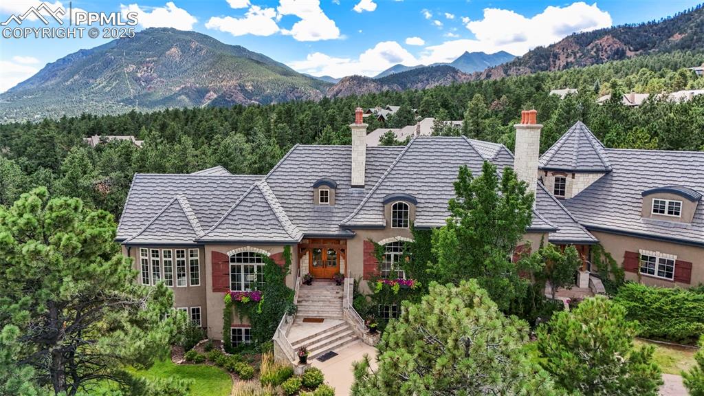 European inspiration… Exceptional architecture, fine craftsmanship, and exquisite materials blend to create this one-of-a-kind getaway in the sought-after Stratton Preserve. Set on two private and tranquil acres, the lot overlooks Cheyenne Mountain to the back and city lights to the front. True quality is on display as you enter the house. Flagstone entry extends through the main corridor. The great room-style living and dining room features vaulted ceilings, dormer windows, and a wood-burning fireplace at each end. The spacious gourmet kitchen connects the hearth room to the back, opening a cozy, entertaining patio. The front landscaping is mature and designed for low maintenance, while the back contains lush gardens and a water feature. On the main level is the primary suite with tandem baths, a large walk-in closet, and a study with a gas fireplace and built-ins. Above the spacious four-car garage is a guest suite with a living area. The lower level contains three en-suite bedrooms, a large recreation room, a wet bar, an extensive wine cellar, and a theatre room. The home is close to the Stratton Open Space, District 12 schools, downtown, hospitals, and I-25.
