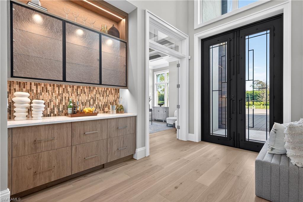 Foyer entrance featuring light wood-style flooring, french doors, and a dry bar