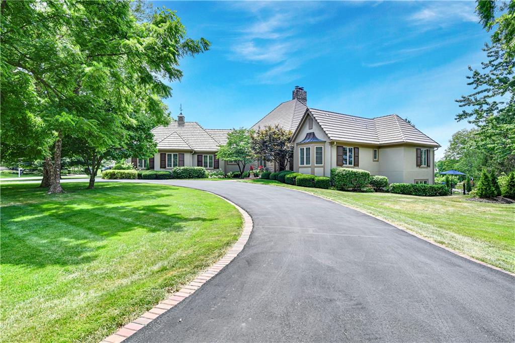 Experience refined living and ultimate privacy in this fully renovated reverse 1.5-story estate on nearly an acre in the prestigious gated golf community of Loch Lloyd. Blending sophisticated design with resort-style amenities, this home offers an unparalleled lifestyle.
Step inside to soaring 13-foot ceilings and walls of windows that flood the open layout with natural light. The heart of the home is an entertainer’s dream, featuring a spacious kitchen with Cambria countertops, dual sinks, custom built-ins, and premium appliances. The space flows into the hearth and great rooms, anchored by a striking see-through fireplace and wet bar. Enjoy year-round outdoor living with a sparkling saltwater gunite pool, updated with plaster, tile, coping, fountains, lighting, and cool-deck finish. Entertain on a Trex deck, a screened-in porch with built-in heaters, fans, TV, and a gas line for grilling. The main-level primary retreat offers a bay window and a spa-inspired bath with heated floors, walk-in shower with jet sprays, and custom closets. The versatile walkout lower level is
perfect for guests and recreation, and boasts a full bar, second kitchen, two bedrooms, flex room with elevator access, and walkout to the pool area. The 4-car side entry tandem garage includes epoxy floors, drains, a utility sink, and ample space. Enjoy numerous modern comforts and smart features including new high efficiency HVAC (2021), Nest thermostat, Ring doorbell, central vac, LED lighting, water filtration, and enhanced insulation. Recent updates include a concrete tile roof, mahogany shutters and doors, $50K in landscaping (2024), sunroom addition with heated floors and mini-split HVAC, plus redesigned kitchen, bathrooms, railings, lighting, and flooring. A rare opportunity to own a fully updated, move-in ready estate in one of Kansas City's most exclusive communities. See supplements for a complete list of updates.