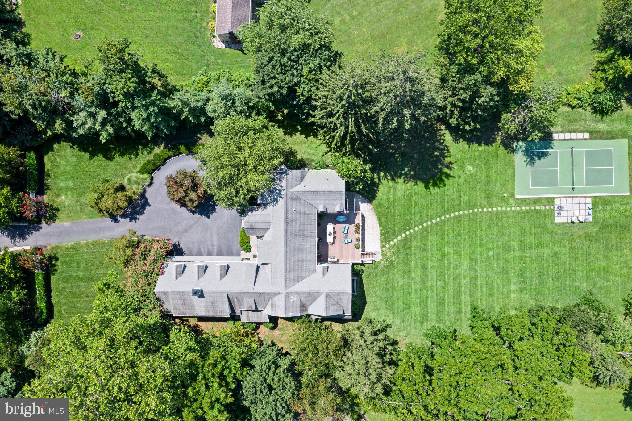 Rare opportunity to watch sunsets in your backyard with your very own pickleball court! Distinguished by its timeless New England architecture and idyllic 1.6-acre setting, 225 Sugartown Road delivers exceptional curb appeal with its white hardiboard siding, charming front portico, slate patio, beautiful front landscaping, and a cobblestone-lined circular driveway framed by a white picket fence and dual lantern lampposts. Custom built with architectural design by renowned local architect Warren Claytor, this estate colonial home offers sun-filled living spaces, rich hardwood flooring throughout the main floor, superior craftsmanship, and a remarkably thoughtful layout designed for both formal entertaining and relaxed everyday living.A charming front door with divided glass panels and matching sidelights opens into a grand foyer highlighting a beautiful turned staircase, crisp white millwork, and soothing neutral tones. What truly elevates the main level is its exceptional architectural design—wide, stately hallways effortlessly connect and separate the living spaces, creating an undeniable sense of grace and flow throughout. To the left, a light-filled formal living room centers around a fireplace with a detailed white paneled surround and handsome mantel. A formal powder room is located nearby. The hall leads to a quiet library featuring its own fireplace, with sliding doors opening directly to the rear deck. Across the foyer, the sun-drenched formal dining room features large front windows and opens to the rear hall with glass French doors overlooking the deck and property, while connecting seamlessly via a butler’s pantry equipped with glass-front cabinetry, stone countertops, and a beverage/wine refrigerator.At the center of daily life, the gourmet kitchen offers abundant custom cabinetry, stone countertops, double ovens, and a center island with seating. The adjoined breakfast area is flooded with natural light from large windows and is open to the handsome great room. Here, a classic white coffered ceiling, fireplace flanked by custom built-in bookshelves, and a triple set of windows create a welcoming gathering space. Sliding glass doors lead out to an oversized rear deck overlooking the expansive, private backyard with views. A mudroom with built-in cubbies, informal powder room, back staircase, and direct access to the attached 3-car garage with charming carriage-style doors complete the main floor.The entire second level offers an impressive 5-bedroom, 5-en-suite bath layout, unified by wide hardwood hallways that gracefully balance connection and privacy. The primary suite serves as a luxurious retreat, flowing into a spa-like primary bath, dual walk-in closets, and an adjoining exercise room/sitting room. This flex room directly connects to a neighboring en-suite bedroom—an ideal setup for a nursery, young child’s room, or private suite study. Two additional spacious en-suite bedrooms anchor the main upper hallway. Reached via either the main corridor or the back staircase, a guest wing features a bonus sitting room/den with built-ins, a 5th en-suite bedroom, and a large laundry room.The expansive finished lower level extends the entertainment options with glazed porcelain tile  flooring, a game room, a TV gathering area, a full built-in wet bar, a private sauna, a third powder room, and abundant natural light from large windows.Outdoors, the level rear grounds offer a private sanctuary framed by mature plantings and trees. Step off the deck onto a vast lawn with ample room for soccer or football games, plus a dedicated pickleball court with a slate patio seating area—perfect for outdoor fun and entertaining.Located in the top-ranked Tredyffrin-Easttown School District, this home is just over 1 mile from the Devon Train Station for an easy commute to Philadelphia and NYC, and close to Whole Foods Devon, the shops and restaurants at Terrain, top private schools, local country clubs, and all the premi