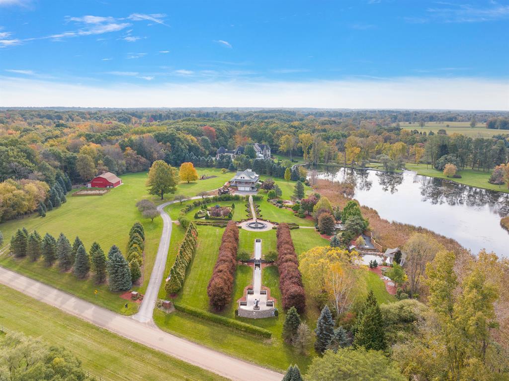 Welcome to a truly exceptional private estate on 10.13 acres in Bruce Township, showcasing a meticulously updated 5-bedroom, 3.5-bath residence with nearly 5,000 finished sq ft of living space, including a walkout lower level with second kitchen, family room, office, and three-season sunroom. The grounds are an oasis featuring a 180-ft reflection pool, Japanese-inspired streams, multiple waterfalls, extensive rockscaping, a semi-private lake. Architectural highlights include a two-story great room, first-floor primary suite, upper-level bridge walkway, gazebo, pole barn, and expansive Trex decking with panoramic views. Included in the sale are three original Jason Napier bronze sculptures valued at $210,400--offered at no cost to the buyer. A rare blend of art, architecture, and nature.