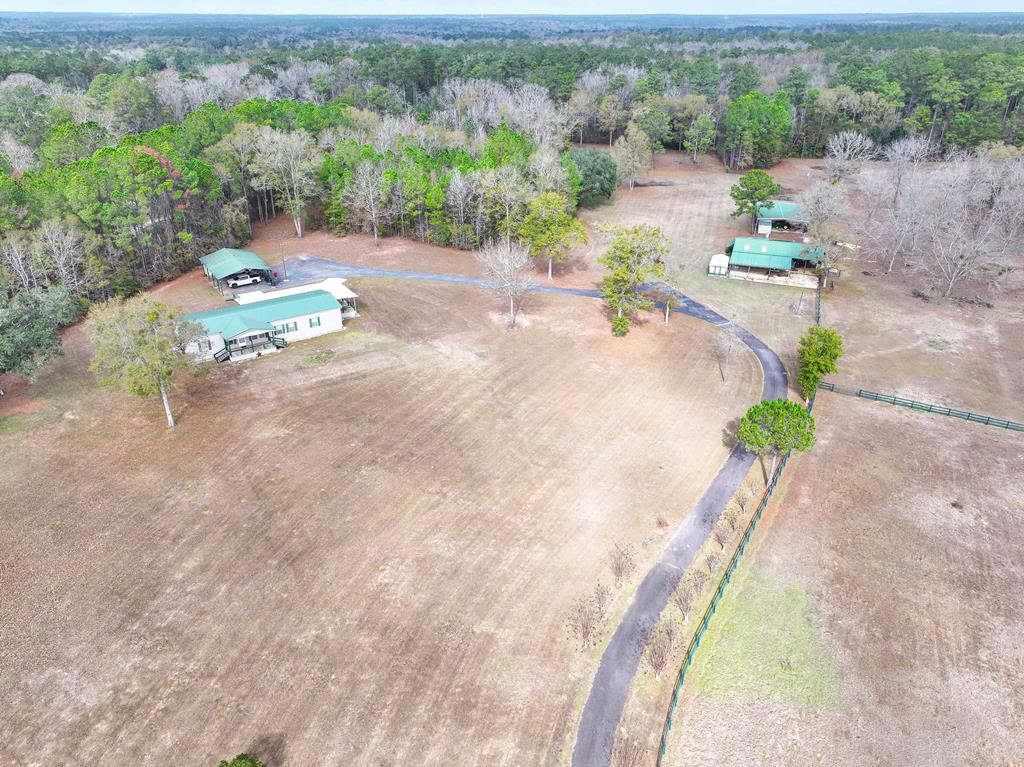 Set behind a gated entrance and perched atop a gentle hill, this exceptional 15.8-acre property at 421 Lewis Road in Cairo, GA offers the perfect blend of privacy, functionality, and Southern charm. Surrounded by beautiful, mature oak trees, the 4-bedroom, 2-bath home enjoys sweeping views overlooking the rolling, fully fenced and cross-fenced acreage—ideal for horses, livestock, or a private country retreat. The home features a durable 2-year-old metal roof and a comfortable, functional layout suited for both everyday living and entertaining. Supporting structures make this property truly stand out. A 40x60 four-stall barn includes a feed room, tack room, and workshop, and is being sold fully equipped with saddles, tack, and a tractor with mower deck, making it a true turnkey setup for equestrian or agricultural use. Additional improvements include a 32x48 pole barn with a concrete floor, perfect for equipment storage or expanded workspace, as well as a bunk house with a full bathroom, ideal for guests, farm help, or a private office or studio. Whether you're seeking a working farm, equestrian property, or peaceful country estate, this rare offering delivers space, infrastructure, and scenic beauty—all just a short drive from Cairo, Thomasville, and Tallahassee.