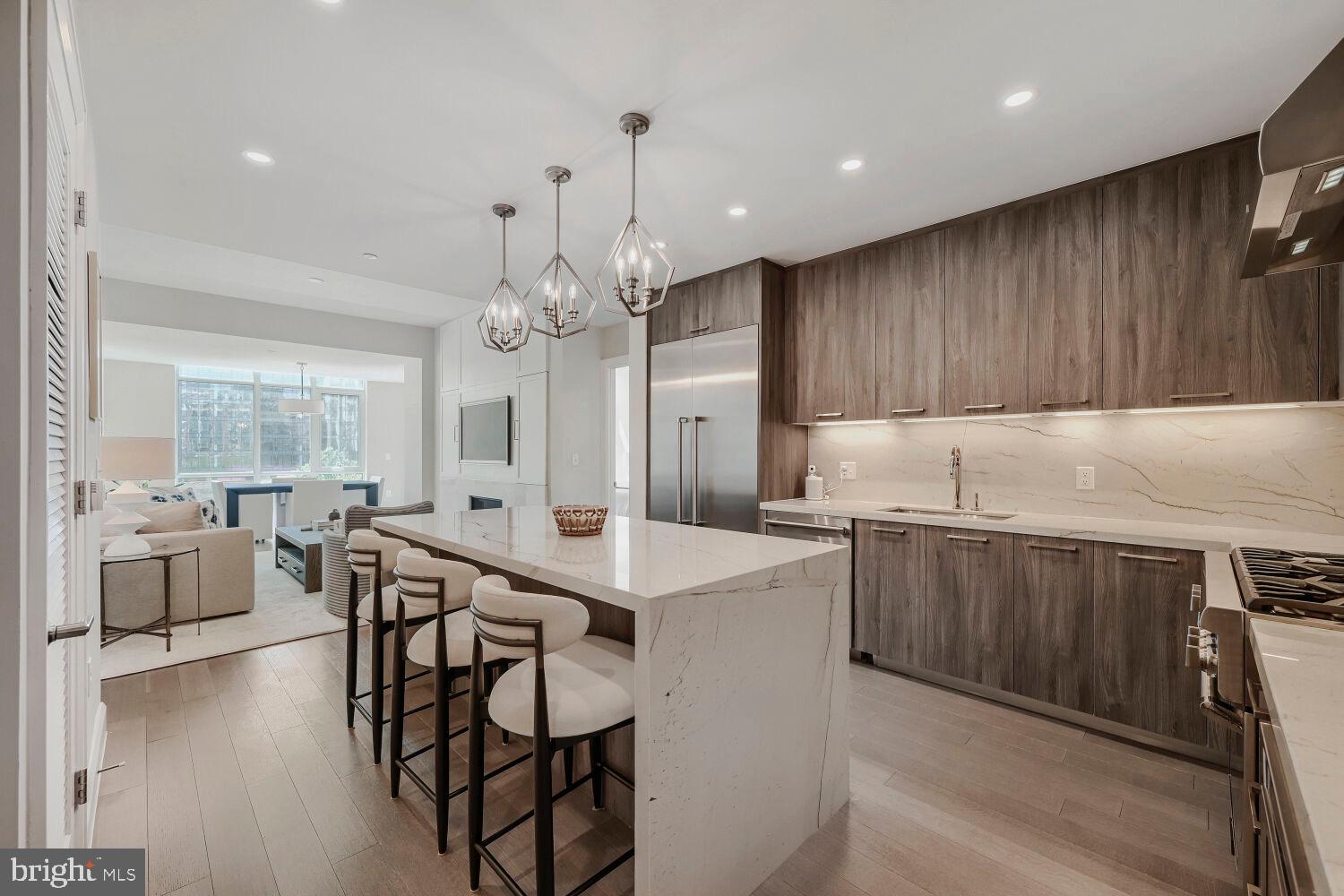 Experience elevated waterfront living at Liberty Harbor East in this sophisticated two-bedroom, two-bath residence showcasing breathtaking water and harbor views from every room. Spanning approximately 1,400 square feet, this impeccably designed home blends modern luxury with effortless elegance, featuring  10-foot ceilings, dramatic floor-to-ceiling windows, wide-plank hardwood flooring, and a custom media wall with gas fireplace. Designed for both refined entertaining and everyday living, the bright and airy open-concept layout is flooded with natural light and framed by captivating harbor and city vistas. The chef’s kitchen is a true showpiece, appointed with sleek Italkraft cabinetry, premium Thermador appliances including a gas range with vented hood and MicroDrawer microwave, and a striking stone waterfall island that seamlessly anchors the living and dining spaces. The serene primary suite feels like a private retreat, wrapped in walls of glass and featuring a spacious walk-in closet and spa-inspired bath finished with Carrara marble, herringbone flooring, Kallista and Kohler fixtures, a frameless glass shower, sculptural soaking tub, and custom dual vanity. The secondary bedroom also offers a generous walk-in closet and beautifully appointed adjacent bath. Complete with one parking space, this exceptional residence places you at Baltimore’s premier luxury waterfront address. Positioned above the flagship Whole Foods Market and surrounded by Harbor East’s finest restaurants, boutiques, and nightlife, Liberty delivers an unmatched lifestyle with more than 30,000 square feet of curated amenities. Residents enjoy concierge service, a social lounge, rooftop infinity pool with cabanas, indoor/outdoor clubroom and bar, fitness center and yoga studio, private dining spaces, coworking lounges, pet park, grilling terraces, and beautifully designed indoor and outdoor gathering spaces  all within Baltimore’s most coveted waterfront neighborhood.