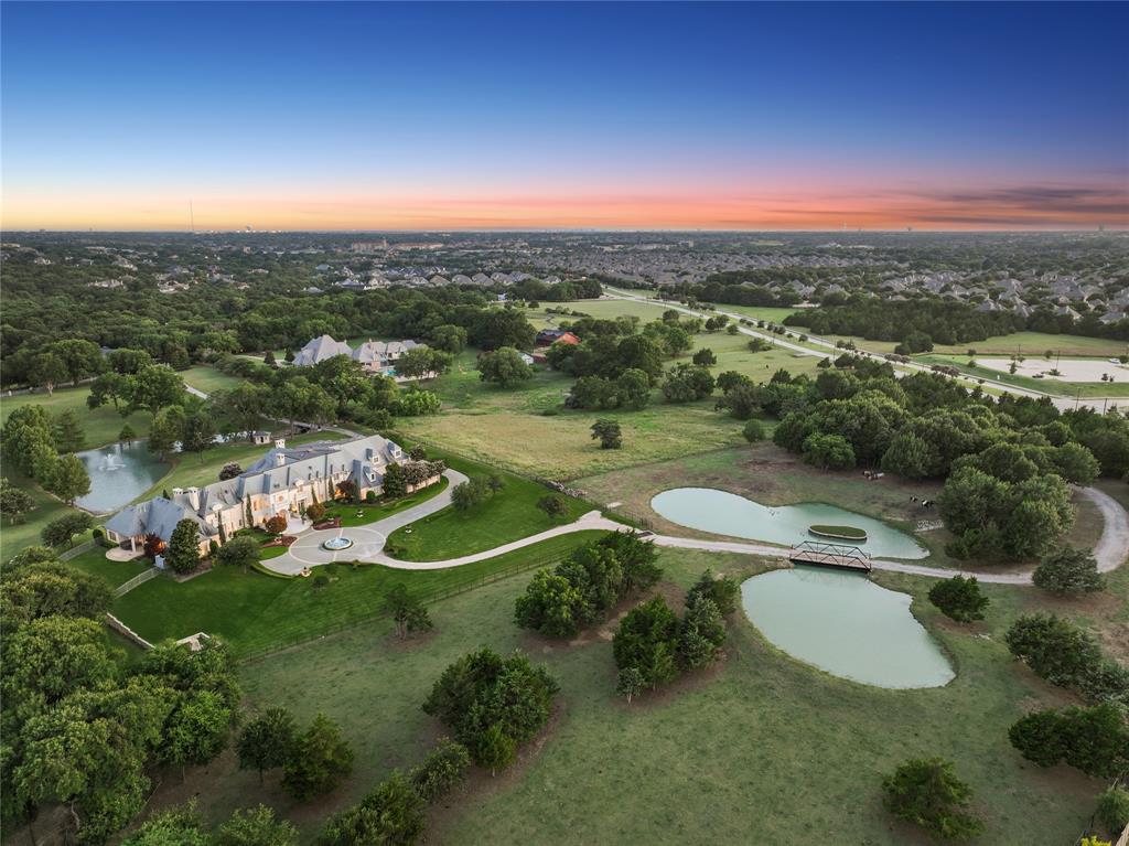 Welcome to Château Lumièr, a private, gated estate nestled on 15 wooded acres with coveted ag exemption, three stocked ponds with fountains, and rare serenity in the heart of McKinney, south of SH 380. Masterfully crafted by Sharif Munir from the finest materials and designed with French Chateau elegance in mind, this architectural jewel balances grandeur and intimacy across every inch. Step through double iron doors into soaring ceilings, gold leaf accents, and handmade Bordeaux flooring. Entertain effortlessly in formal and casual spaces alike, each adorned with bespoke finishes: groin vault ceilings, coffered beams, antique appliqués, and Italian marble. The chef’s kitchen is outfitted with luxury appliances, hand-painted tiles, and custom maple cabinetry, anchored by an impressive China and Silver Room featuring Carrera marble and herringbone wood floors. The Great Room commands attention with cathedral-beamed ceilings and five sets of French doors opening onto the veranda, overlooking manicured grounds and outdoor living anchored by a fireplace and full kitchen. The owner’s wing includes dual bathrooms, dual closets, a second office, a fireplace, a workout room, and breathtaking views. Wine connoisseurs will appreciate the climate-controlled wine room and film lovers, the private media suite with digital projection. A whole home generator, 1000' deep private well, and an elevator reflect the estate’s blend of beauty and self-sufficiency. Relax and enjoy panoramic views from every room of this residence. Additional features include spacious bedroom ensuites with luxe finishes, separate guest quarters with private entrance, full kitchen and 2 bd 2 bth; a mahogany study with pocket office & imported African marble; game + craft rooms, a playhouse with electricity. Château Lumièr isn’t simply a home, it’s a legacy property where artistry meets livability in a world of its own. Attends McKinney ISD.