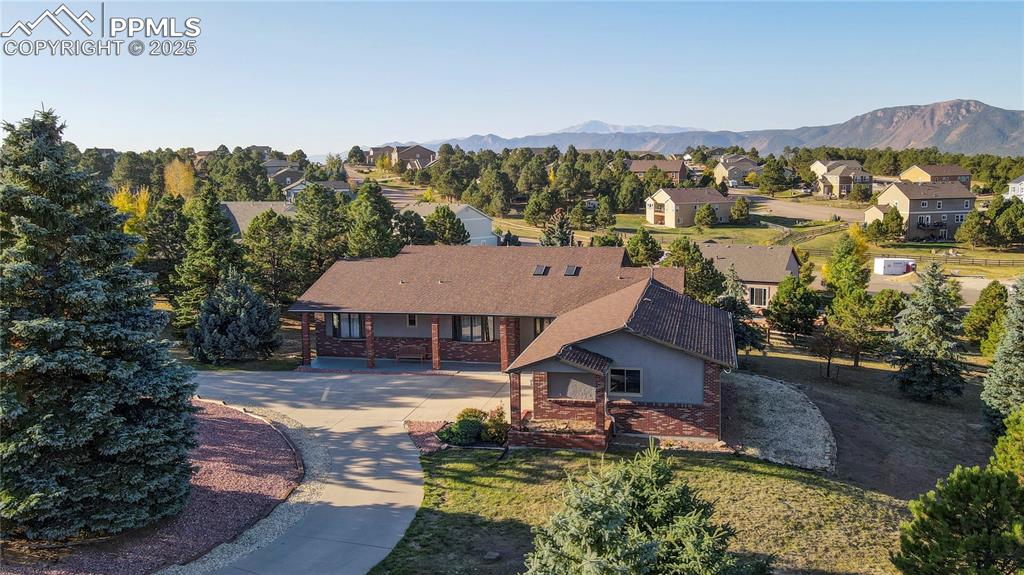 Welcome to your Woodmoor retreat—an upgraded 5-bedroom, 3-bath ranch home with 2x6 construction, main-level living, and a finished walk-out basement. Set on a peaceful 0.68-acre lot with mature trees, this move-in-ready home offers privacy, mountain views, and modern updates throughout. Step inside to find an open, sunlit floorplan featuring hardwood floors, fresh paint, expansive windows, and striking views of Pikes Peak, Mt. Herman, and the Rampart Range. The great room centers around a dramatic floor-to-ceiling brick fireplace and flows seamlessly into the gourmet kitchen, complete with quartz countertops, a custom sink and faucet, JennAir stainless steel appliances, gas range, and a spacious island—perfect for entertaining. The main level also offers a large laundry room with garage access and a private primary suite with walk-in closet, jetted tub, 5-piece ensuite, and direct access to the covered deck. The finished basement includes two oversized bedrooms, a full bath, and a large family room with gas fireplace, ideal for movie nights, a home gym, or game space. An unfinished 30x10 storage room and a 15x30 workshop with 42" exterior access door offer incredible flexibility. Enjoy multiple outdoor living areas including a covered upper deck and shaded lower patio, surrounded by fully fenced yard, garden beds, and concrete walkways. The oversized 3-car garage features new doors and openers. Located in the desirable D38 school district with easy access to I-25, shopping, dining, and outdoor recreation including Palmer Lake, Monument Lake, and the Santa Fe Trail. As a Woodmoor resident, you’ll also benefit from 24/7 community security and optional lake amenities. This one checks all the boxes—schedule your showing today!   NEW CARPET MAIN LEVEL JULY 7, 2025