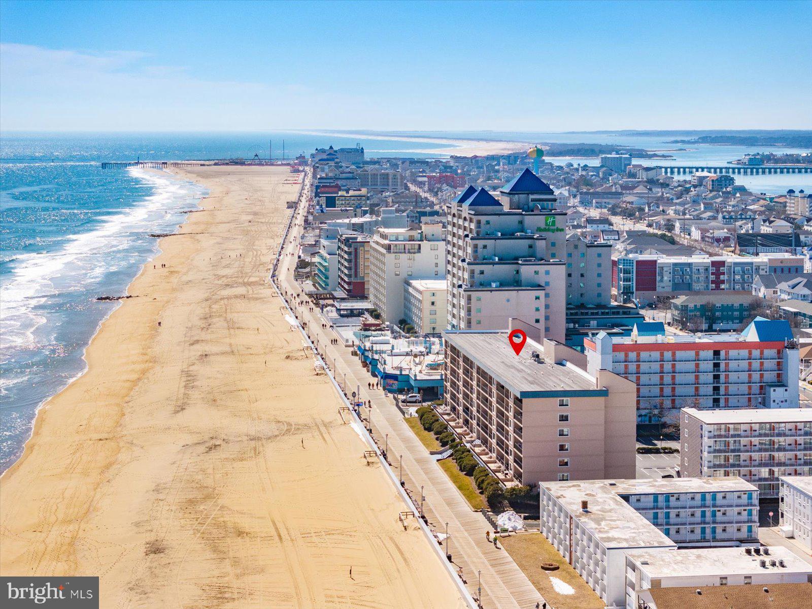 1801 Atlantic Ave. Unit 402, Ocean Hideaway, Ocean City, MD is a fully renovated 2-bedroom, 2-bath oceanfront residence offering 1,067 square feet of refined coastal luxury in one of the most desirable brick buildings on the north end of the boardwalk. Completely transformed with high-end finishes and beautiful furnishings, this turnkey condominium showcases sweeping ocean and boardwalk views from its open-concept living spaces. The designer kitchen is both elegant and functional, featuring soft-close cabinetry with abundant storage, quartz countertops, a tiled backsplash, stainless steel appliances including a recessed refrigerator, recessed lighting, and a center island with seating and additional storage, accented by nautical pendant lighting that enhances the relaxed coastal aesthetic. A spacious pantry with automatic lighting adds convenience, and the kitchen flows seamlessly into the dining area and expansive living room, where beautifully appointed furnishings and generous seating create a warm and inviting gathering space. Sliding glass doors open to a private oceanfront balcony—an ideal place to enjoy sunrise views and listen to the crashing waves along the Atlantic shoreline. The oceanfront primary suite offers breathtaking water views, direct balcony access, and the opportunity to fall asleep and wake up to the sound of the waves, while the ensuite bath is updated with a walk-in shower and modern finishes. The hall/guest bath has been beautifully renovated with a fully tiled tub surround, glass doors, new vanity, and updated lighting. The second bedroom is well-appointed with decorative headboards and convenient under-bed storage with a functional footboard storage bench, offering both style and practicality for guests. A separate full laundry room with upper and lower cabinetry and a quartz countertop adds exceptional storage and convenience. Ceramic tile flooring runs throughout the residence, complemented by custom window treatments and updated lighting fixtures. Ocean Hideaway is a professionally managed brick building with reserve funds, secure keyed elevator lobby access, direct beach and boardwalk access, outdoor foot shower, and one assigned parking space. Sold fully furnished and equipped, this exceptional residence offers excellent rental potential and is ideal as an investment property, second home, or full-time oceanfront retreat—just steps from restaurants, shopping, amusements, beach concerts, and fireworks along the world-famous Ocean City boardwalk.