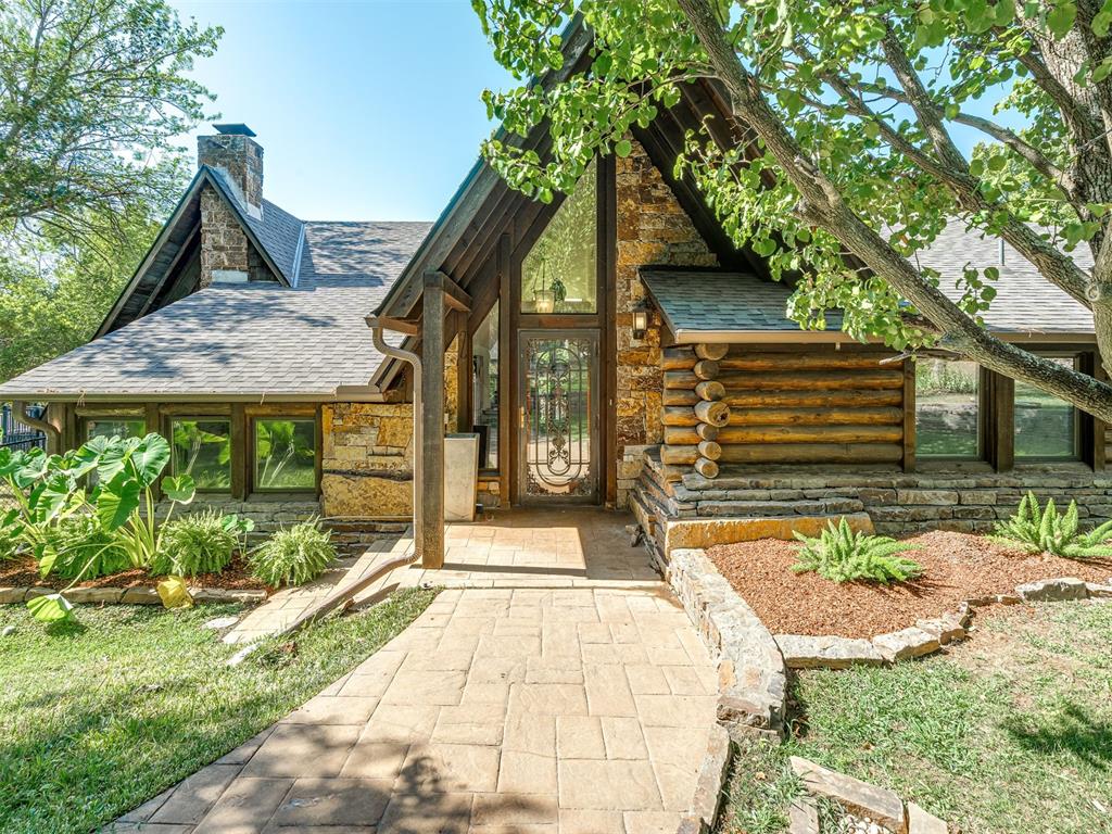 Just a mile off the highway yet worlds away in feel, this 32-acre (MOL) retreat offers a cozy but rustic home-away-from-home minutes from the city — or a distinctive setting for a business with privacy, acreage, and easy highway access. A striking log-and-stone grand home sits tucked into mature woods along a running creek with its stacked-stone walkway leading beneath a canopy of trees to a soaring, glass-and-timber entry.Inside, a two-story great room impresses with vaulted, beamed ceilings, skylights, a wall of windows, and a floor-to-ceiling stone fireplace. An open loft above, reached by a rustic log-and-timber stair, adds a treehouse-like bunk room lined in real log siding. The kitchen was fully remodeled with two-tone cabinetry, glass-front display cupboards, butcher-block counters, a farmhouse sink, a professional-grade range, and hand-glazed tile backsplash. A hearth room with its own stone fireplace and window seat, plus a light-filled sunroom, add flexible living space. The primary suite offers an oversized custom walk-in closet and a spa bath with dual vanities, a soaking tub, and a glass tile shower.Outside, a free-form pool with concrete surround patio awaits as well as a private lighted tennis court that sits among the trees. Across the creek, a gated, secluded 20-acre parcel includes a bonus tiny home (not included in the home's square footage) with potential as a guest house or getaway cabin with some renovation. This is truly a prime piece of property — gated, secluded, and open to nearly any use: raise animals in a heated, surveillance-equipped barn, run a business with endless possibilities, or simply enjoy it as a private sanctuary close to the city. There have been numerous recent updates to this property.  Ask for your copy!  Buyers to verify schools. Please provide bank letter or Preapproval letter prior to showing.