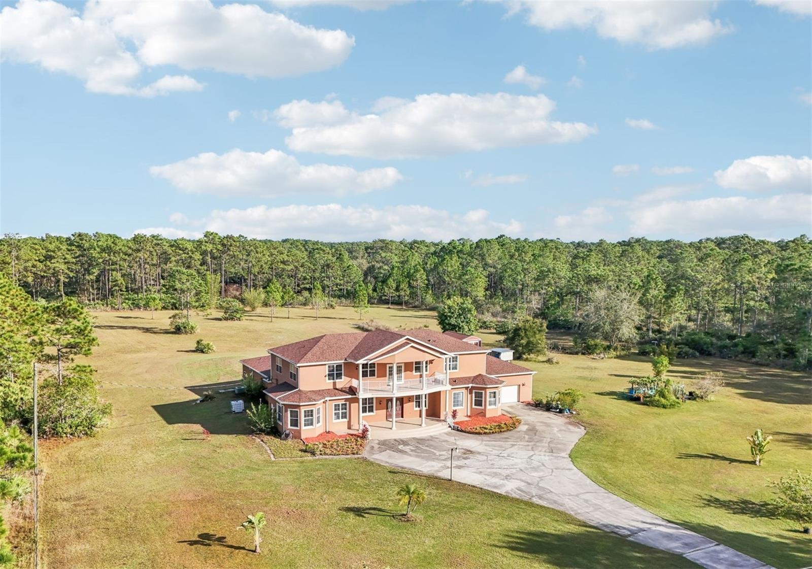 One or more photo(s) has been virtually staged. Dreams do come true! Welcome to your private slice of paradise in Wedgefield! This impressive custom-built estate offers over 5,000 square feet of living space with 6 bedrooms and 6 bathrooms, beautifully set on 4.77 acres and zoned A-2, so you can bring your horses, goats, chickens and more. Built in 2004 and well-maintained, this property blends peaceful country living with modern convenience and community amenities, including an 18-hole golf course, playgrounds, sports courts and nearby Hal Scott Preserve for hiking, biking and nature lovers. A 5-foot wrought iron fence spans the 360-foot front yard with a 20-foot wrought iron electric gate and pedestrian gates on either side, while the rest of the property is enclosed with 5-foot wire fencing- ideal for animals and added privacy. The enormous front and back yards are perfect for play, gardening, entertaining and enjoying the quiet setting, and the 288 sq. ft. Tuff Shed provides excellent additional storage. Step up to the Shark Coating front porch and through the double-door entry into a grand foyer that sets the tone for the rest of the home. Gorgeous inlaid porcelain tile flows throughout the first-floor living areas, and arched vaulted ceilings add volume and elegance. To one side of the foyer is a welcoming sitting room, and to the other, a formal dining area ready for large gatherings. The spacious, open kitchen anchors the main level with granite countertops, a granite breakfast bar, recessed lighting, abundant cabinetry and a huge walk-in pantry. The open concept layout connects all the spaces, giving you endless options for arranging living, dining and entertaining spaces to suit your lifestyle. On one side of the main floor you will find a guest bedroom with its own private bathroom featuring a Jacuzzi tub with shower - great for visiting guests or multi-generational living. The opposite side of the home hosts two individual office spaces, each with its own exterior entrance and one with a half bath, creating an ideal setup for remote work, home-based business, studio or hobby spaces. The main floor primary suite is a true retreat, complete with a tranquil sitting area and separate dual walk-in closets. The expansive primary bath offers a glass-enclosed shower, luxurious Jacuzzi garden tub and dual vanities, giving you a spa-like experience at home. French doors from the main living area open out to an approximately 1,100 sq. ft. screened lanai with porcelain tile flooring and a peaceful forest view. This impressive outdoor living area includes counter space with cabinets, a sink and a convenient half bath - perfect for hosting parties, enjoying quiet mornings with coffee, or relaxing after a long day without ever leaving your property. Up the grand curved staircase, a loft area opens to a balcony overlooking the front yard, giving you yet another beautiful space to relax or gather. Four additional bedrooms extend off the loft, two on each side, and each pair of bedrooms is served by a bathroom with a Jacuzzi tub and shower. One of the upstairs bedrooms features its own private sunroom, adding even more flexible living space for a reading nook, playroom, workout area or creative studio. This home is truly impressive - offering space, serenity and versatility inside and out! Come experience the peaceful setting and spectacular location for yourself. Call today to schedule your private showing an ASK US ABOUT THE ASSUMABLE VA LOAN or LENDER PROVIDED RATE BUY-DOWN CREDIT!