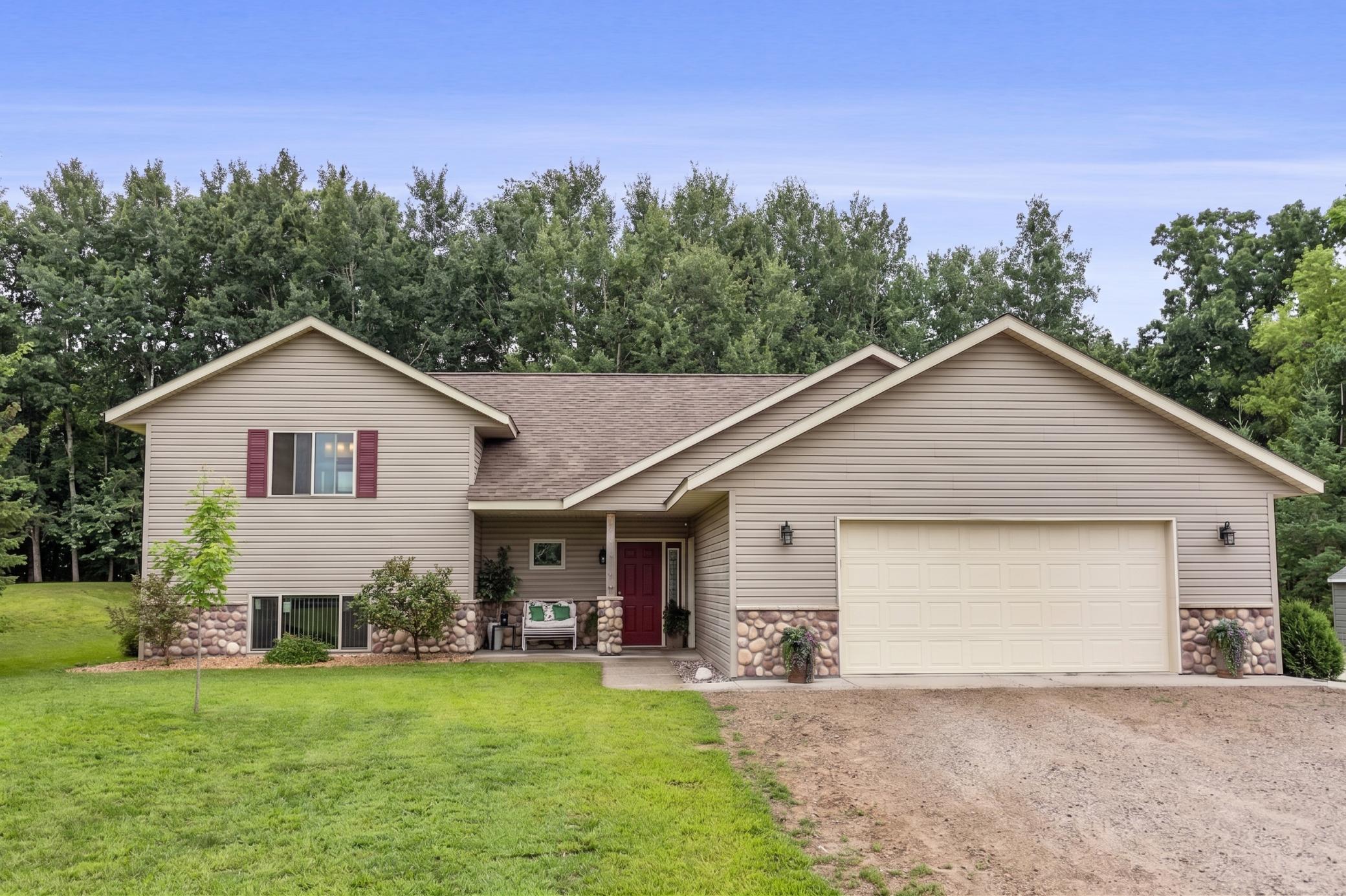 Welcome to your private slice of country living! Custom-built in 2019 and set on over 5 sought-after acres.This 3-bedroom, 3-bathroom home offers the rare combination of newer construction and true acreage living. Step inside to an open floor plan with custom Hickory cabinets, quartz countertops and a bright living space.The Main floor features a private primary ensuite, vaulted ceilings and a walk out to a relaxing patio. Downstairs, the finished lower level offers a family room, 1 bedroom and ¾ bathroom and ample storage. The attached oversized garage is fully finished with hot & cold water, a floor drain and heating source. Outside is where this property truly shines. Surrounded by woods & privacy, relax by the bonfire or on the front porch. Bring your animals and toys, with a 40x50 outbuilding with a lean-to in place, already set up with electric and an additional sand point well near by. Additional outbuildings for the camper, storage, chickens and everything you dream. Opportunity to expand buildings or pasture, bale hay or build a riding arena.This property checks the boxes for space, function, and quality construction all in one.
