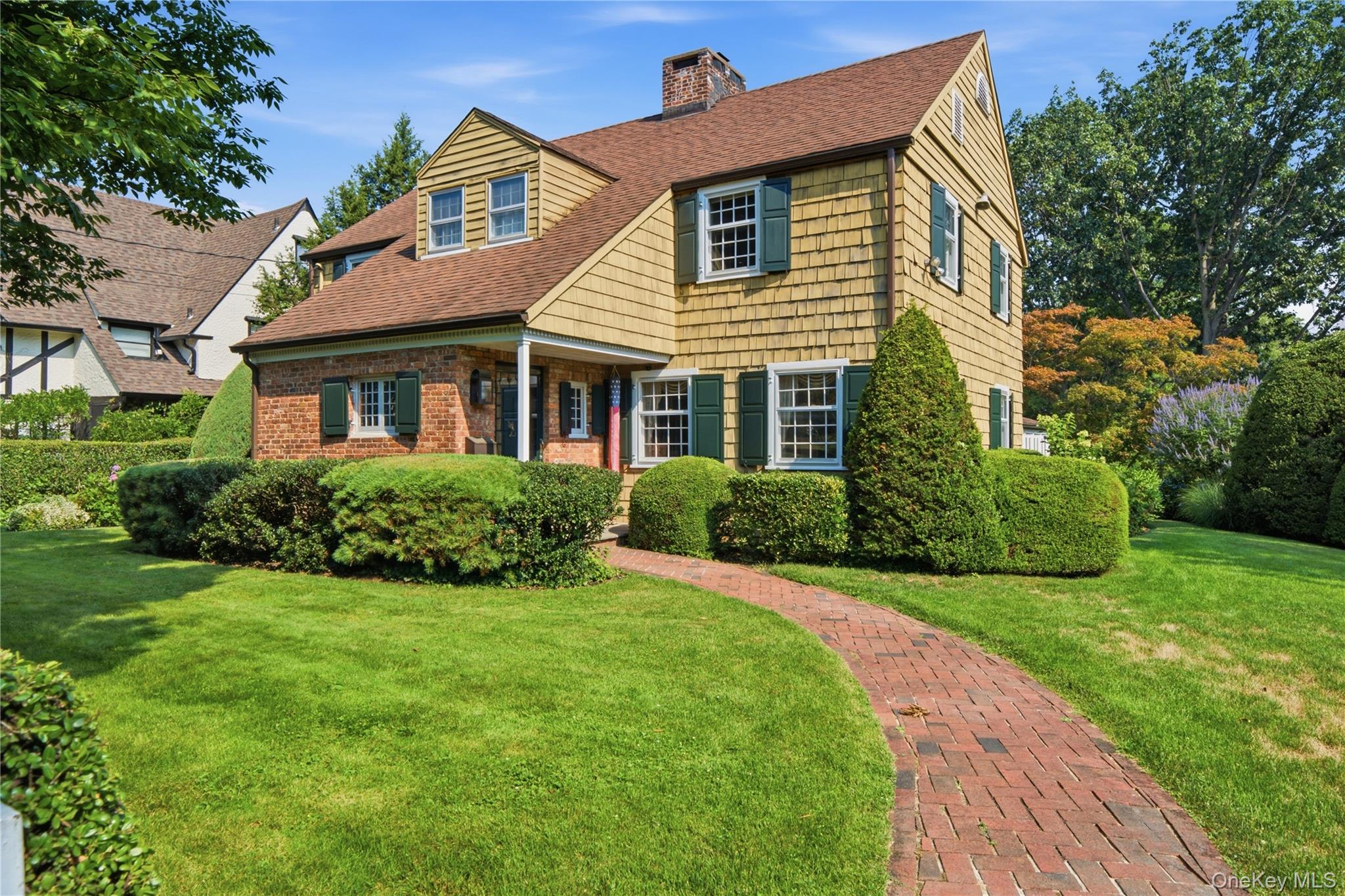 Perched atop prestigious Douglas Manor on a beautifully landscaped 9,200-square-foot corner lot, this classic Colonial offers timeless character, exceptional craftsmanship, and modern updates. A gracious wood-paneled entry hall welcomes you with multiple access points to the main living spaces, a convenient powder room and a coat closet. The expansive living room showcases original wide-plank hardwood floors, exposed beamed ceilings, rich wood trim, and a striking wood burning fireplace, while oversized windows bathe the space in natural light. Original solid wood doors connect the living room to both the formal dining room and entry hall, preserving the home's historic charm. Just off the foyer is a versatile first-floor room with an adjoining full bath, ideal as a guest bedroom, home office, den, or playroom. The bright eat-in kitchen features oversized windows, a custom butcher-block countertop, built-in microwave, dishwasher, and newly installed wood flooring that extends into the original pantry, where abundant cabinetry provides exceptional storage. A door from the kitchen leads to the porch and backyard deck, creating an easy indoor-outdoor flow for entertaining.The formal dining room is a true showpiece, featuring original wide-plank floors, decorative crisscross ceiling beams, an impressive gas fireplace, built-in corner cabinets, custom wallpaper, and coordinating draperies. A charming Dutch door opens to the sunroom, where two walls of windows overlook the beautifully landscaped grounds, creating the perfect setting for morning coffee or quiet relaxation. The second floor offers four bedrooms, a linen closet, and a built-in bookcase in the hallway. The spacious primary suite features two large closets, an en-suite bath, recessed lighting, and three windows that fill the room with natural light. The additional bedrooms offer generous proportions, ample closet space, and original hardwood floors beneath the carpeting, with two currently serving as a home office and TV room.The lower level is divided into four functional spaces, including a laundry room with a washer, dryer, and double utility sinks, along with abundant storage. A heated two-car garage with interior access provides year-round convenience, complemented by an additional carport with access from East Drive.Rich in architectural detail, history, and warmth, this exceptional Douglas Manor residence presents a rare opportunity to own a distinguished home in one of the area's most sought-after neighborhoods.HOA fee $900.00 annually.