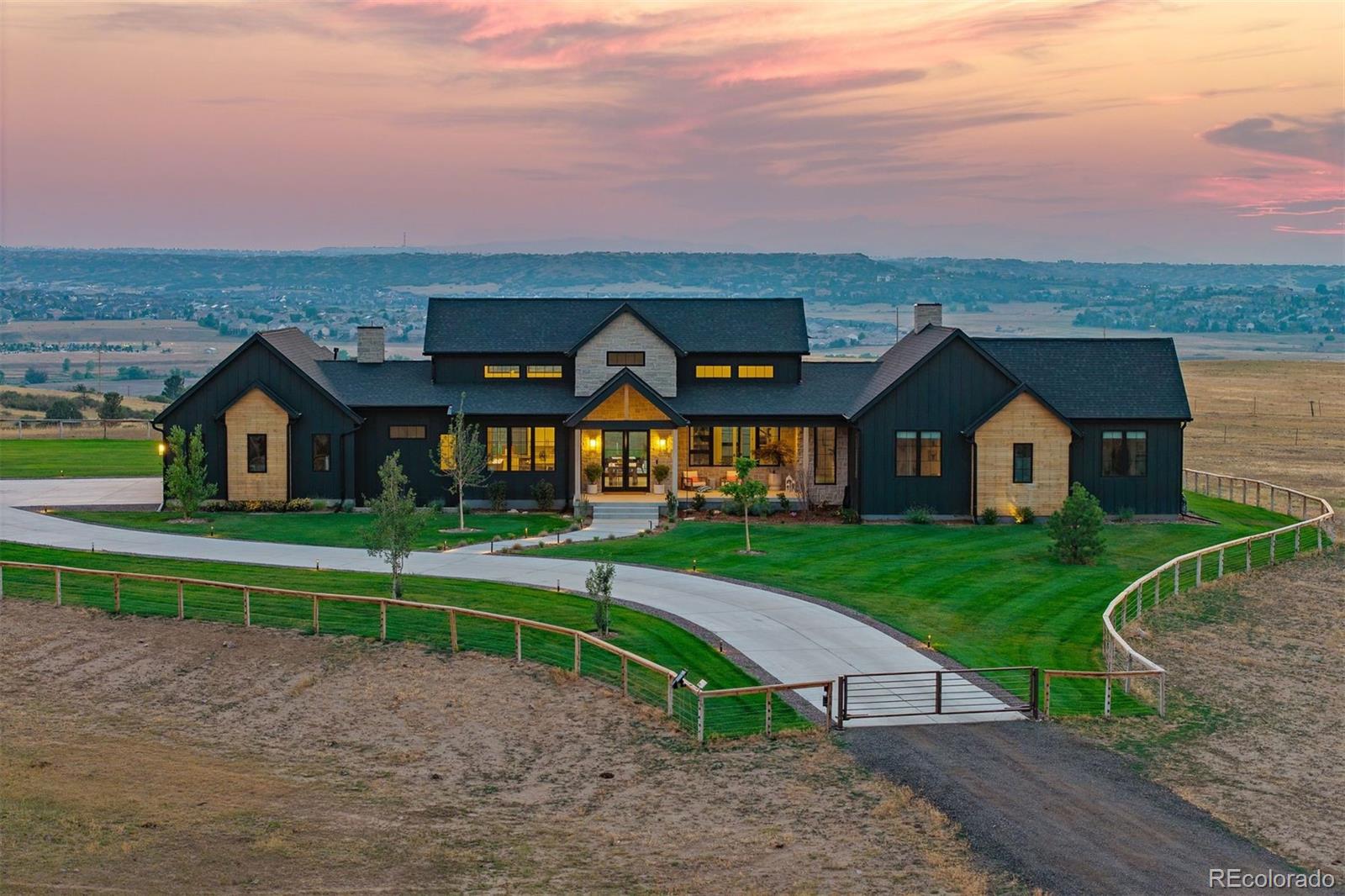On 35 gated acres in Franktown, a modern farmhouse with industrial flair puts Front Range views, from Pikes Peak to the Flatirons, on permanent display, with a saltwater pool & outdoor kitchen – You may never want to leave home again! Built in 2023 in the exclusive Fox Ridge neighborhood, the home sets crisp, modern lines against rolling fields ideal for grazing, riding, or breathing room, plus an exceptional 8,400 sq ft heated workshop with drive-thru doors, upstairs level with offices & conference room, & 2 baths. Honed concrete floors ground a 20' vaulted great room, where a 16' multi-slide door erases the line between patio & mountain view. A linear fireplace framed by built-in bookshelves creates an intimate sitting area. The kitchen matches the scale: 2 islands, quartzite counters, JennAir® appliances, & a chef's walk-in pantry so cleverly disguised as cabinetry that guests will need directions.The primary suite offers floor-to-ceiling glass framing Pikes Peak beneath a 14' vaulted ceiling. A barn door opens to a spa bath finished in quartz, with a freestanding tub and a 6'x14' shower with dual everything: entries, rain shower heads, & controls. A custom walk-in closet connects straight to the laundry room. Lower level offers a rec room, wet bar, 2 bedrooms sharing a bath, & an exercise room.A covered patio houses a linear gas fire pit & an outdoor kitchen with gas grill and flattop, set against mountain views. A 16'x32' saltwater pool, with a sun shelf, stretches across a half-acre lawn. A pool bath keeps the party outside. Smart home technology for lighting, shades, pool, & security.When your need for a workshop is beyond just a hobby. A 60'x140' shop offers multiple garage doors & a mezzanine with 3 offices, a conference room, & 2 baths. Fenced pasture and access to Bayou Gulch Open Space and riding trails to the north complete the property. 10 minutes from the shops & restaurants of Parker and Castle Rock, near Douglas County Schools.