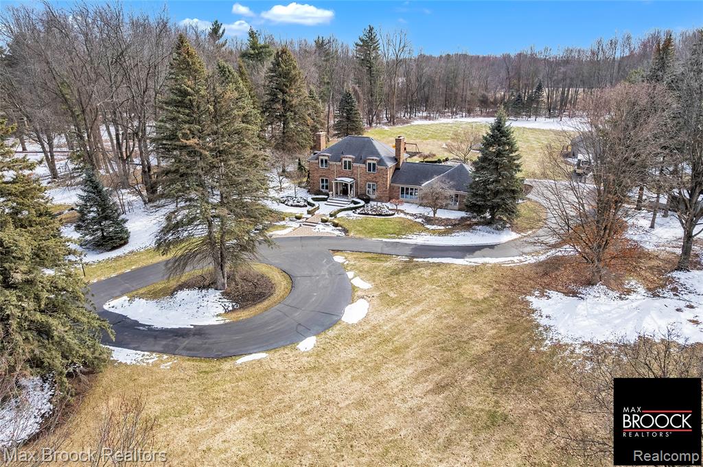 An extraordinary opportunity to own a private gated estate set on five pristine acres in the heart of Farmington Hills, tucked gracefully from the road and enveloped by mature trees, offering a rare blend of seclusion, scale, and everyday convenience. This exceptional residence features over 2,500 square feet of thoughtfully designed living space, including three spacious bedrooms and 2.5 well-appointed baths. Expansive living and entertaining areas are filled with natural light and showcase tranquil views of the surrounding grounds, while the beautifully appointed kitchen serves as the true centerpiece with custom cabinetry, rich wood flooring, luxurious granite countertops, and premium stainless steel appliances, flowing seamlessly into the open living and dining areas anchored by a stunning fireplace, along with a distinguished main-level library. The sweeping acreage presents limitless possibilities for a resort-inspired outdoor retreat, curated gardens, or future expansion, complemented by an attached two-car garage, additional large detached storage garage, and extended driveway, full-house generator, and recently installed A/C unit, hot water heater, and furnace, completing this remarkable estate offering. Lot is splitable, survey attached in documents.