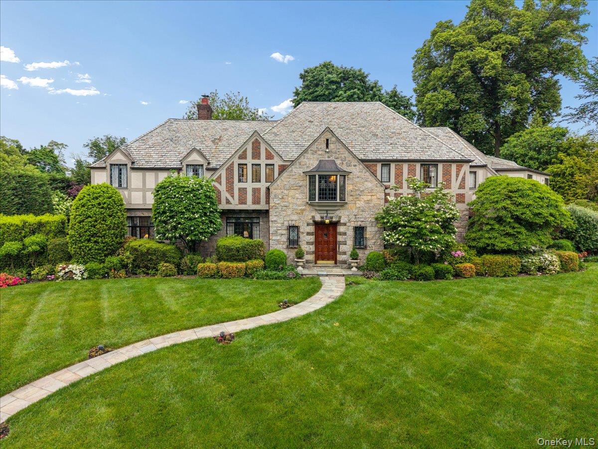 Set on over half an acre in the heart of Pelham Heights, this 1936 English Tudor offers arare blend of timeless architectural beauty, modern luxury, and exceptional privacy.Meticulously maintained and in pristine condition, this brick-and-stone residenceshowcases remarkable craftsmanship, period details, and thoughtfully updated livingspaces. At the heart of the home is a spectacular open-concept chef's kitchen featuring radiant heated floors, premium appliances, gas fireplace, and a dedicated HVAC system. Just beyond, the formal dining room comfortably accommodates large gatherings, while the sunken living room spans the front and rear of the home, highlighted by rich wood paneling and wood-burning fireplace. The wood-paneled library offers a warm, intimate space, while the sunroom, wrapped in leaded windows, adds warmth, charm, and natural light throughout.The second floor is thoughtfully arranged into three distinct wings, offering privacy andflexibility. The primary suite is surrounded by windows and features multiple closets anda newly renovated spa-like bath. Adjacent to the primary suite is an additional privatebedroom suite with its own bathroom. Beyond custom wooden doors are threegenerously sized bedrooms, including one with an en-suite bath and two sharing arenovated bath. A separate wing of the upper level includes another full bathroom,laundry room, oversized walk-in cedar closet, and a bedroom/office with separateaccess to the kitchen, driveway, and backyard. The finished lower level offers a fully equipped gym and an entertaining area with storage. The outdoor living space rivals a private resort, featuring a gated patio, a private saltwater pool, and an expansive deck. Cypress and spruce trees surround the property, creating extraordinary privacy. This exceptional home offers timeless style, generous living space, and modern comfortin one of Pelham’s most desirable neighborhoods. Centrally located near town, train, and schools.
