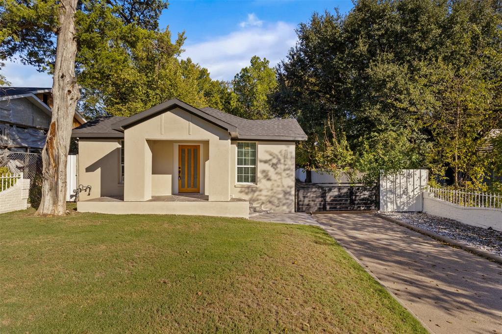 View of front of home featuring stucco siding, a patio area, and roof with shingles
