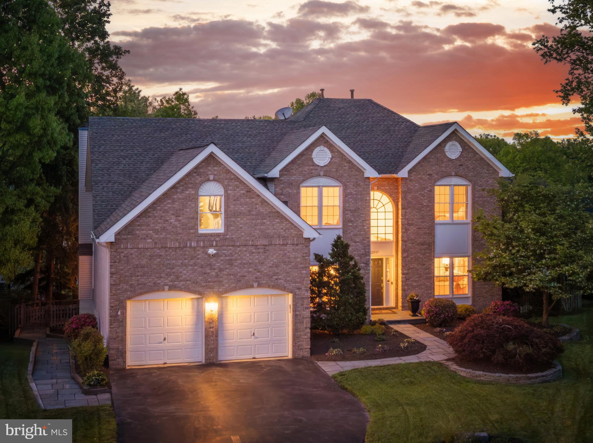 12537 Ridgegate Drive is the kind of home buyers hope to find and rarely do: a brick-front colonial with over 5,000 finished square feet on three levels, set at the end of a quiet cul-de-sac on an extremely private fenced lot with beautiful landscaping, room to play, and outdoor spaces that actually feel usable. From the moment you walk in, the home feels bright, warm, and generous, with sunlight pouring through the many windows and skylights, hardwood floors across the main level, recessed lighting throughout, and a layout that gives everyone space without losing the comfort of a true home. The main kitchen is designed for real daily living, with 42-inch white cabinetry, granite counters, stainless steel appliances, an island with seating, a walk-in pantry, wine fridge, and the kind of storage that keeps life organized. It opens to large gathering spaces, including a dramatic family room with soaring ceilings, skylights, and a gas fireplace, creating a central place to relax, host, watch the game, or spend a quiet night in. A main-level office with French doors and a full wall of custom built-ins gives you a proper work-from-home space, while the formal living and dining areas add flexibility for holidays, dinner parties, music rooms, homework zones, or whatever the next season of life requires. Upstairs, the primary suite feels like a true retreat, with hardwood floors, a spacious sitting area, a massive walk-in closet with custom built-ins, and a beautifully updated bath with heated floors, a towel warmer, custom marble counters, dual sinks, a frameless glass shower with multiple shower heads and a bench, soaring ceilings, skylight, and a private water closet. Three additional upper-level bedrooms are bright and comfortable with generous closets and ceiling fans, and the updated hall bath has the polished, timeless feel buyers want without needing to take on a project. Bedroom-level laundry adds everyday convenience, because no one wants to carry laundry up and down three levels if they do not have to. The walkout lower level is what makes this home especially flexible, offering a full bedroom, full bath, built-in bar or kitchen area, great entertaining space, and direct access to the rear stone patio. Whether you need space for guests, long-term family, an au pair, a private work area, a game room, or simply a second living zone, this level gives you options that most homes do not. Outside, the composite deck off the kitchen overlooks the private backyard, while the stone patio below creates another place to gather, grill, relax, or let the yard become the backdrop for everyday life. The oversized two-car garage, approximately 35 by 20 feet, offers incredible storage with ceiling storage on multiple walls, making it ideal for bikes, tools, sports gear, seasonal decor, and everything else that usually ends up without a home. The major updates are already handled, including roof and skylights in 2017, HVAC in 2016, water heater and sump pump in 2022, updated bathrooms, and an exterior gas line installed in 2025. The location is just as strong as the home itself, with easy access to downtown Herndon, Reston Town Center, Dulles International Airport, the W&OD Trail, Silver Line Metro stations, major commuter routes, hospitals, parks, trails, pools, golf, the Herndon Community Center, farmers market, concerts, restaurants, and all the daily conveniences that make this part of Northern Virginia so livable. Spacious, private, bright, flexible, and beautifully positioned, this is a home that gives buyers the room they need now and the options they will appreciate for years.