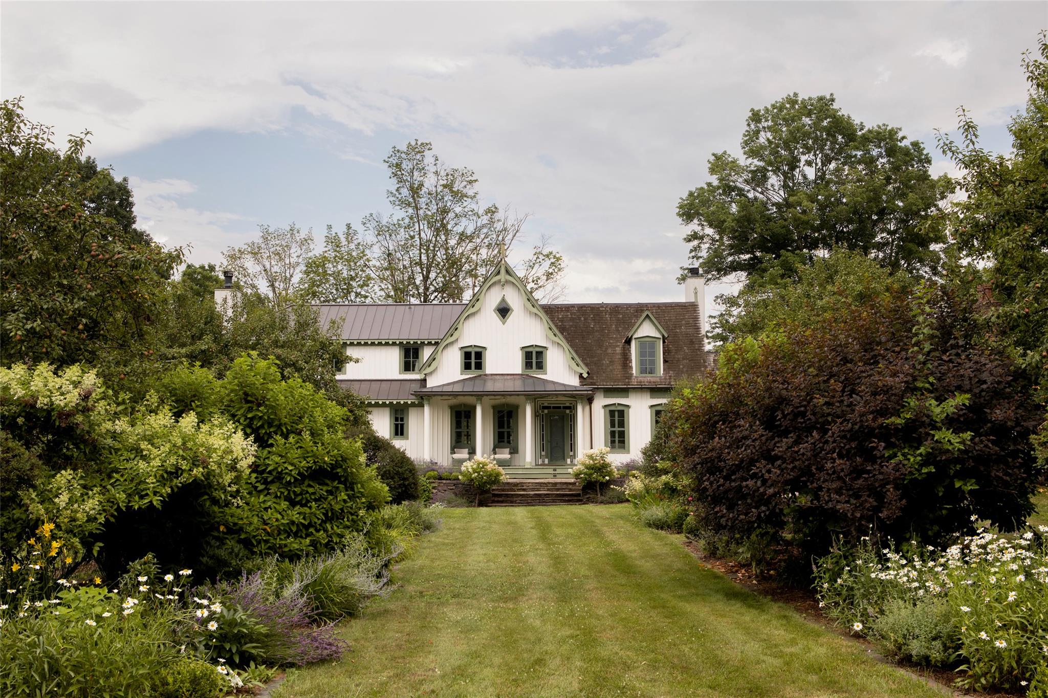 Nestled near the meeting point of the Hudson & Camp Creek on three & a half splendidly landscaped acres, Peary Homestead is a well-preserved & abundantly charming example of the 19th-century Gothic Revival country manor.
The home was built in the 1840s by ship captain Robert Peary & would stay in his family for nearly a hundred years, serving as a farm with far-reaching pear orchards.
The current owners continued expanding the bountiful gardens, while also undertaking, with the help of architect Chip Bohl & interior designer Louise Copeland, a complete interior renovation & the construction of the north wing, home to the kitchen & the primary suite.
The guiding purpose of the recent multi-year-long renovation was to unify each space within the house, embracing elements of the historical floorplan where possible, & integrating textures & finishes that felt authentic to the property's early 19th-century roots.
In the newly built North wing, the beautifully crafted Plain English kitchen is further enriched with honed Arabescato marble countertops, a deep green Lacanche range, a built-in breakfast nook, & a working fireplace. Ample storage for small appliances & cooking supplies was integrated into the kitchen's millwork, & a separate butler's pantry & bar lead the way to the characterful dining room, which features a vibrant green limewash by Portola Paints & the most precious views of the property's central allee gardens & greenhouse.
The 'formal' living room centers around a particularly tall fireplace, lending itself to more intimate evening gatherings & slow weekend afternoons lounging with a book. The family room, on the other hand, finds its home in the sunroom, an energetic & bright space constantly in dialogue with the surrounding gardens & exterior entertaining spaces. A library/office with walls of overflowing built-in bookshelves, a gym, a wallpapered powder room, a tiled mudroom, & a large screened-in porch complete the ground floor.
The home's original staircase leads to the second-floor landing, with sweeping views of Peary's fruit trees & endless gardens. The primary suite is very well-fitted, with two dressing rooms / walk-in closets, & a large bath with a soaking tub, Waterworks vanity & fixtures, & shower.
Two identical kids' rooms with built-in cabinets & tall ceilings share a bath. The guest suite is in the original wing of the home, & is covered in creamy, textured wallpaper, with extra tall windows that look out onto the front courtyard, a walk-in closet, & a full bath. Second-floor laundry is discreetly fitted into the back section of the home, with a secret door leading to the very magical playroom for the small ones.
The second floor of the carriage house hosts a large guest flat, with tall, vaulted ceilings, two bedrooms, a dining/gathering area, & a full bath. The ground floor houses much of the utility & workspace for the property, with a 2-car garage, storage, & a workshop that, because of its verdant views & abundance of natural light, equally lends itself to the artist or maker as it would a gardener.
Every inch of Peary Homestead's land is overflowing with charm & whimsy - from the in-ground pool with two lotus gardens along its sides, to the custom greenhouse with a fenced cutting garden, & a long line of trellissed raspberry bushes, the pear trees as a special nod to the property's history, the trumpet-vine covered dining pergola, a babbling stone fountain, the oh-so-gently tamed field of wildflowers, & many an allee to wander down, all lined with the most magical flowers & plants.
Peary Homestead is near a wealth of beloved farm stores, restaurants, orchards, hiking spots, & charming towns. The property is just minutes from Germantown's main street, 10 minutes from Hudson / the Amtrak train station, 20 minutes from Red Hook, Tivoli, & Rhinebeck, & 2 hours from New York City.