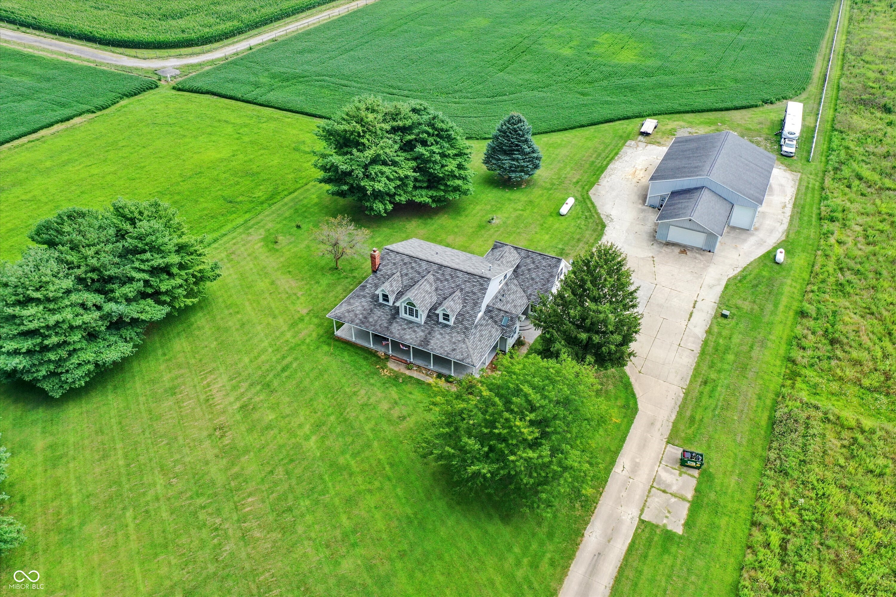 Although it carries a Franklin address, this property is actually located in Bargersville and sits within the highly desirable Center Grove School District. Nestled on 11.5 scenic acres, this 4-bedroom, 4-bath farmhouse offers over 3,300 sq. ft. of charm, space, and versatility. Seven of the acres are already being farmed-future owners can keep that arrangement if they'd like, which means only about 3 acres would need personal upkeep. There's also an income opportunity for anyone who continues leasing those acres for farming. From the welcoming covered front porch to the sun-filled kitchen and cozy great room with fireplace and built-ins, every detail invites comfortable country living. The main-level primary suite includes a jacuzzi tub, dual vanity, and walk-in shower. Upstairs you'll find three bedrooms, two full baths, and two flexible den areas-perfect for home offices, playrooms, or creative spaces. Enjoy serene views from the sunroom or host gatherings on the spacious back porch. Outside, this property truly shines. Outbuilding #1 (24x28) is heated with epoxy floors, ideal for a workshop or hobby space. Outbuilding #2 (58x50) includes 12-foot garage doors, upstairs storage, and room for RVs, equipment, or even a home business. With a wrap-around gravel drive, generous parking, two HVAC systems, and wide-open land ready for gardens, animals, or future expansion, this home offers the best of both country retreat and modern convenience-just minutes from town.