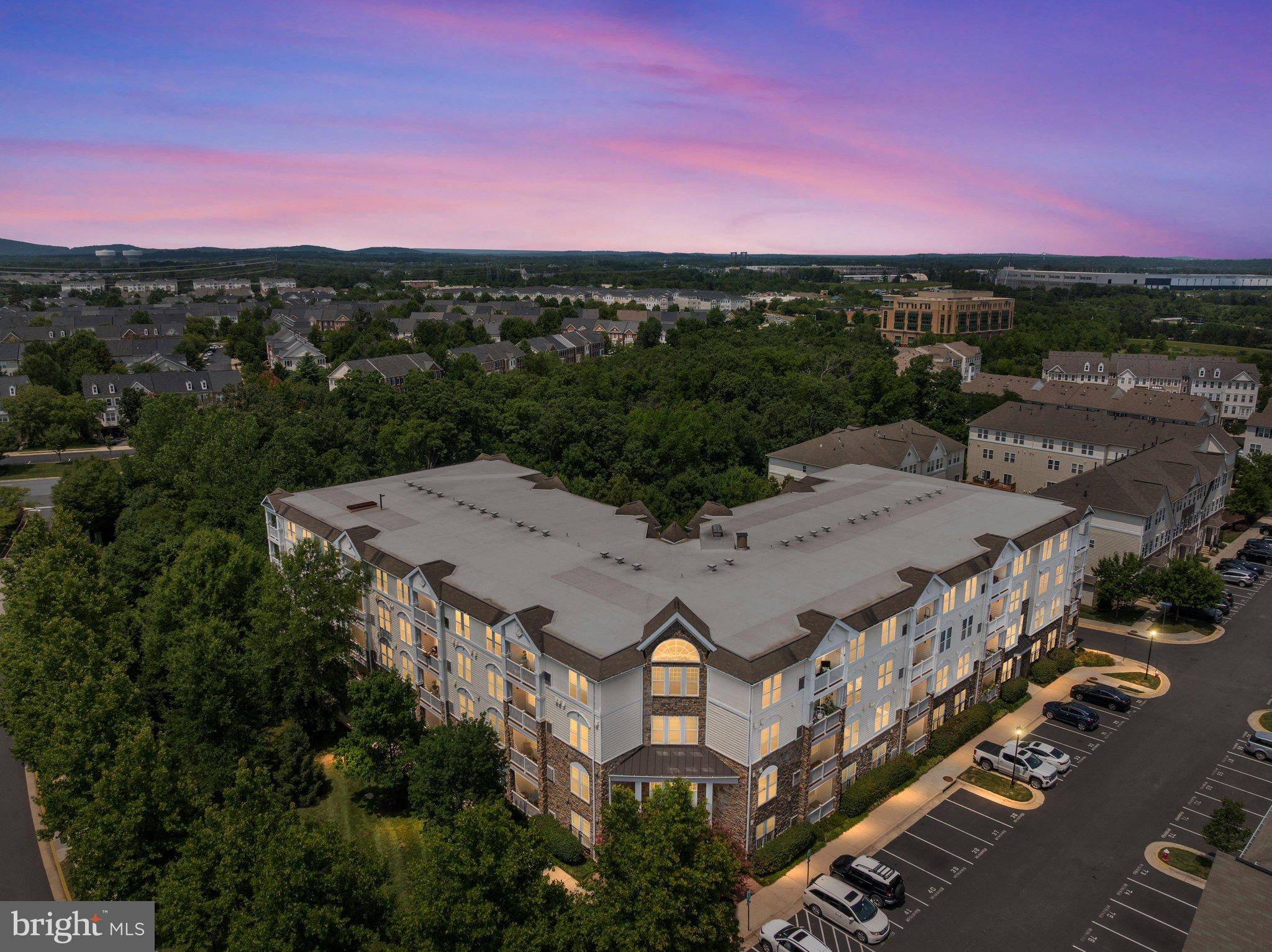 **Join us for an Open House on Saturday, August 22 from 2:00 - 4:00PM and Sunday, August 23, from 1:00 to 3:00 PM.** Welcome Home! This beautifully maintained Mercer Park elevator condominium offers the perfect combination of comfort, convenience, and low-maintenance living. This spacious 1,105 square foot home features 2 bedrooms, 2 full bathrooms, garage parking, an additional reserved parking space, and a private balcony with beautiful sunset and treetop views. Step inside and you will immediately appreciate the high 9-foot ceilings, oversized windows, and abundance of natural light that create a bright, open, and inviting atmosphere. The upgraded kitchen features upgraded cabinetry, stylish granite countertops, ample storage, and a convenient dining area that flows effortlessly into the spacious living room perfect for everyday living and entertaining. Just off the living room, step outside onto your private balcony with plenty of room to relax with your morning coffee, unwind with a book, or enjoy beautiful sunsets overlooking the trees and distant mountain views. The thoughtfully designed floor plan provides added privacy. The spacious primary suite is located on the opposite side of the living area from the secondary bedroom and features a large walk-in closet and private en-suite bathroom. The generously sized second bedroom is conveniently located near the additional full bathroom, making it ideal for guests, a home office, or flexible living space. Enjoy the convenience of a secure building with elevator access from the garage to every level. One garage parking space is included, along with an additional reserved space in the street-level parking area. The building has no age restrictions and features wide doorways designed for ease of accessibility. The location is exceptional! Enjoy convenient access to shopping, dining, and everyday conveniences at Stone Ridge Village Center.  Community amenities include building and elevator maintenance, secure building access, trash service, a clubhouse with fitness area, and an inviting community pool. Commuters will appreciate the easy access to Route 50 and surrounding Northern Virginia destinations. Don't miss this wonderful opportunity to enjoy spacious, low-maintenance living in the heart of Stone Ridge. Schedule your private showing today!