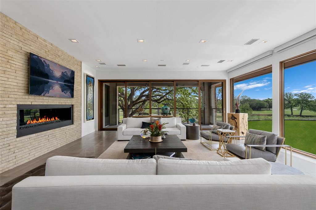 17214 Club Hill is a refined expression of modern luxury, thoughtfully reimagined and expanded in 2020 to nearly 8,964 square feet. Taken to the studs, the residence was rebuilt with all new systems—electrical, plumbing, HVAC, insulation, windows, and roof—and enhanced by integrated Control4 technology for seamless whole-home audio, video, lighting, and security. The interiors are expansive yet composed, defined by floor-to-ceiling Pella architectural windows and multi-slide doors that frame sweeping views across two fairways and White Rock Creek. Level 5 wall finishes, porcelain concrete flooring, custom wood ceiling panels, and stone feature walls create a layered architectural backdrop, while dual floating staircases with integrated lighting serve as sculptural focal points. Linear fireplaces, motorized Lutron shades, and curated lighting further elevate the atmosphere. The kitchen is both functional and beautifully appointed, featuring a large center island, Thermador appliance suite with gas range, double ovens, warming drawer, and dual dishwashers, along with a butler’s pantry and secondary refrigeration. Additional spaces include a wine and whiskey room, media room with 120” screen, game and billiards room, private office, guest suite, and generous laundry and storage. Outdoor living is intentionally layered, with a multilevel pool and spa, firepit, and terraced landscaping positioned to capture the home’s elevated vantage point. Motorized screens create seamless indoor-outdoor transitions, while a circular drive, detached three-car garage, and HOA-maintained grounds offer a true lock-and-leave lifestyle. Bent Tree is entering a new chapter with a 65,000-square-foot clubhouse and a course transformation by Beau Welling. Long recognized as a premier golf destination, the Desmond Muirhead-designed course is being thoughtfully reimagined, complemented by exceptional racquet facilities and a culture of excellence.