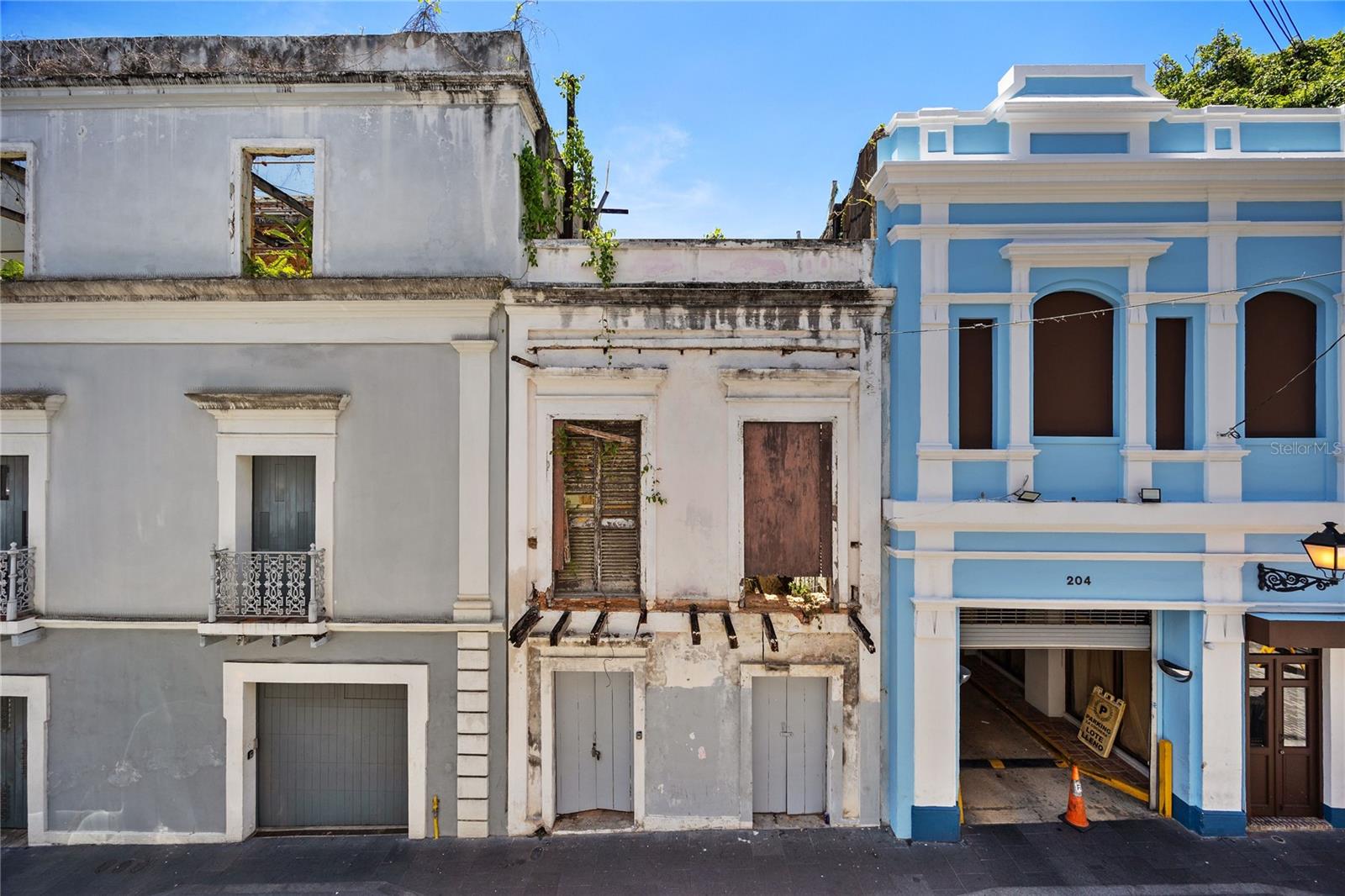 Set along a quiet stretch of Luna Street in Old San Juan, just a block and a half from Plaza de Armas and immediately adjacent to La Cochera, this beautifully preserved historic ruin offers something increasingly rare: authenticity, history, and presence. Originally built as a three-story townhouse, the structure reveals itself in layers:  aged masonry, rhythm of arches, and a depth that unfolds gradually from the street, drawing you inward. Inside, the atmosphere is unexpectedly still, almost reverent. Sunlight filters through the open volume where floors and roof once stood, illuminating textures shaped by time. Trailing vines, weathered plaster, exposed beams. The original courtyard opens dramatically upward, revealing the full height of the structure, while remnants of the staircase and upper levels remain visible, offering a striking sense of verticality and proportion. A space that holds memory, where architecture and nature have quietly intertwined.  For those who understand it, the opportunity is clear. The current owner has commissioned architectural plans for a three-story residence, designed in keeping with the property’s proportions and townhouse scale. Set within one of the most desirable and walkable pockets of Old San Juan, this is a project defined not by what is missing, but by what can be brought back, with intention, with respect, and with vision.