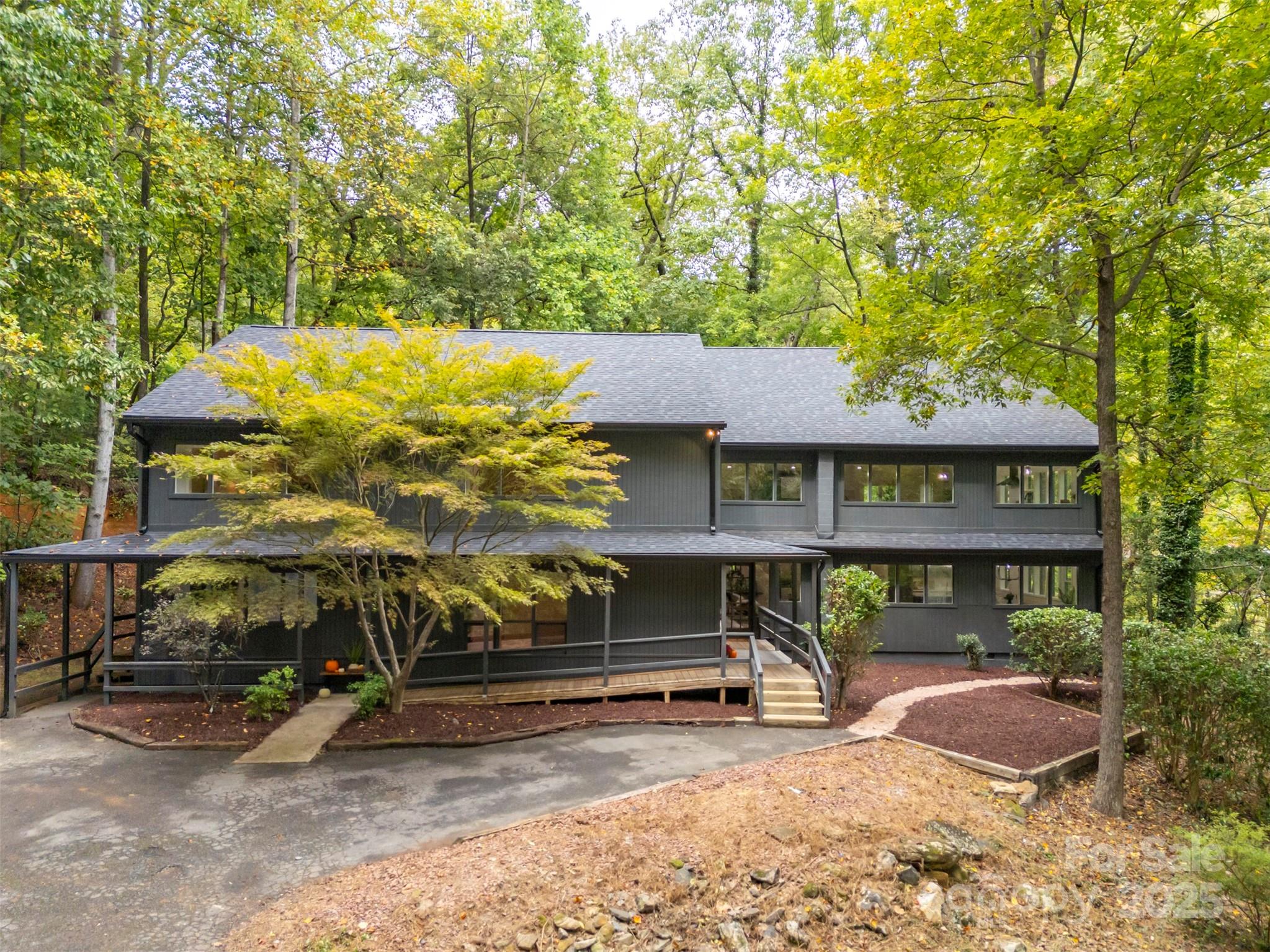 Nestled amongst towering hardwoods on a 10acre parcel, this stunning contemporary home represents an extraordinary find.  While just minutes from downtown Tryon & I-26, the property sits at the end of a quiet cul-de-sac for optimal privacy. A gently flowing creek runs along the lower boundary line w/nature conservancy woods behind plus long range winter views.  Technically a reverse floor plan, each level boasts a full kitchen, living/great room area, primary suite and laundry - an ideal situation for multi-generational living or an investment rental property.  Impeccable finishes from the gorgeous herringbone inlay oak in the foyer to the starburst tile in the guest baths to the warm charcoal stained cabinets throughout.  Ground level features a huge mudroom/laundry w/custom drop zone cabinetry & folding island, entertainment room w/80" TV, spacious kitchen w/breakfast bar & dining area, plus a sitting/living room & convenient powder bath.  En-suite primary plus 4 additional bedrooms and 2 shared baths.  Head upstairs to a cavernous great room w/gas fireplace and rear deck.  Sleek & modern kitchen surrounded by picture windows w/ample area for dining.  Additional sitting room, bonus room & hall bath plus another laundry.  Principle primary is set apart at the end of the hall for perfect restfulness.  Lounge or reading area, spacious walk-in closet & striking walk-in tile shower with bench.  Exquisite home w/endless possibilities!