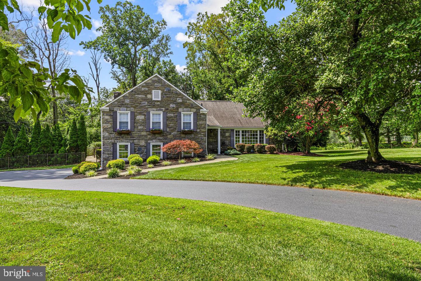 A rare opportunity in one of Radnor Township’s most desirable locations, this beautifully updated greystone residence offers the privacy, setting, and sophisticated living today’s Main Line buyer is seeking. Tucked away at the end of a quiet cul-de-sac and adjacent to the picturesque grounds of Overbrook Golf Club, the property feels remarkably secluded while remaining convenient to everything that makes Radnor so coveted.Step inside and discover a home that is as impressive in scale as it is in style. Newly installed flooring flows throughout the residence, complementing a thoughtfully renovated and exceptionally flexible floor plan. At the heart of the home is a gourmet island kitchen designed for both everyday living and effortless entertaining. A gracious formal living room features a newly renovated fireplace surround, while the inviting dining room with bar creates an elegant setting for intimate dinners and larger gatherings.Just beyond, a spectacular Great Room addition opens across the rear of the home, with soaring vaulted ceilings and beautiful views of the private grounds. This light-filled space creates a seamless connection between indoor and outdoor living—and leads to a backyard that feels like a private resort.Surrounded by mature privacy trees, perennial gardens, flowering shrubs, and a wooded landscape bordering Overbrook Golf Club, the outdoor setting is truly exceptional. Expansive patios provide multiple areas for dining, entertaining, and relaxing around the in-ground swimming pool and spa. Whether hosting a summer gathering or enjoying a quiet afternoon by the pool, the setting offers a level of privacy that is increasingly difficult to find in Radnor Township.The upper levels provide equally impressive accommodations. The luxurious Primary Suite features generous walk-in closets and a beautifully appointed spa bath. An additional bedroom and full hall bath complete this level. Just six steps above is an expansive second suite with an en-suite bath, abundant closet space, and substantial attic storage. Its generous proportions offer tremendous flexibility and could easily be reconfigured to create two separate bedrooms.The lower level adds yet another comfortable living area, with a mudroom conveniently accessed from the two-car garage, a second Family Room with fireplace, and a powder room. Also an unfinished basement provides lots of storage space. Designed to evolve with its next owner, the home’s flexible floor plan offers the potential for four or five bedrooms, making it equally suited to sophisticated entertaining, working from home, extended family, or changing needs over time. A whole-house generator provides additional comfort and peace of mind year-round.Private. Spacious. Beautifully updated. And positioned at the end of a cul-de-sac in an exceptional Radnor Township setting. Opportunities combining this degree of privacy, outdoor living, flexibility, and location are exceedingly rare on the Main Line.
