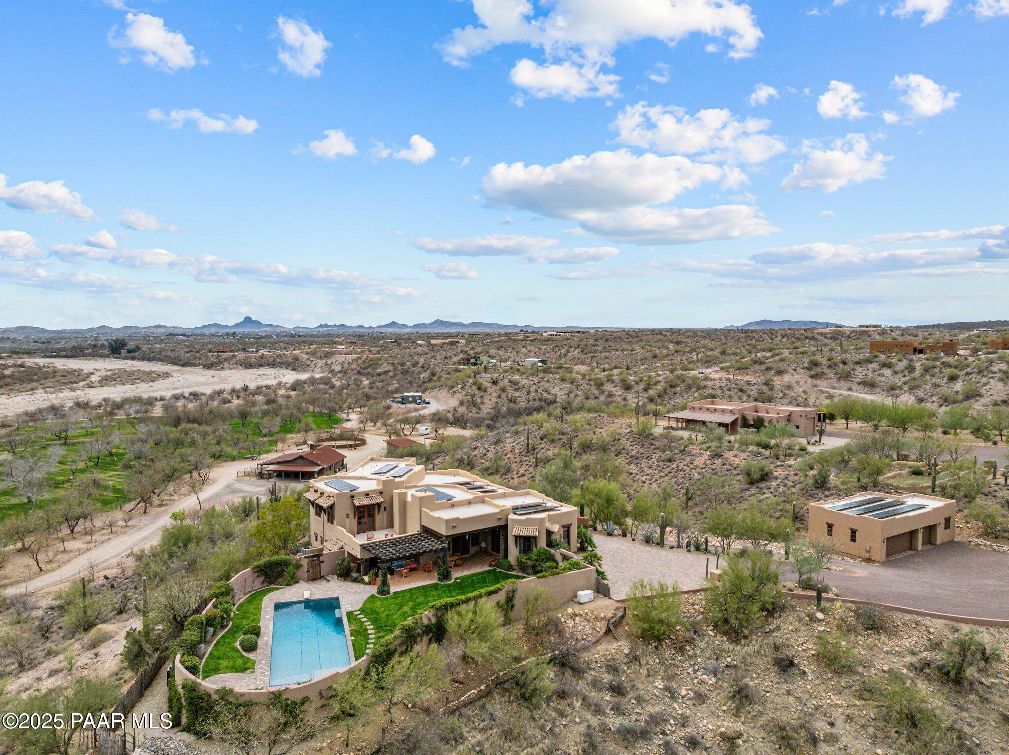 An Extraordinary Equestrian Retreat in the Heart of WickenburgWelcome to one of Wickenburg's most exceptional equestrian estates--a rare offering where luxury, privacy, and the authentic spirit of the American West come together in perfect harmony.Perched on 34 pristine acres overlooking the tranquil Hassayampa River, this remarkable Territorial/Santa Fe masterpiece, designed by the acclaimed Chaves & Associates, commands breathtaking panoramic views of Arizona's spectacular Sonoran Desert. Here, endless sunsets, towering saguaros, and star-filled skies create a setting that is both inspiring and unforgettable.The beautifully crafted residence offers nearly 4,000 square feet of sophisticated Southwestern living. Rich architectural details, warm Western character, and expansive windows invite the surrounding landscape indoors, creating an atmosphere that is both elegant and welcoming. The thoughtfully designed floor plan features three spacious bedrooms, a private den or fourth bedroom, and four full baths. A luxurious split primary suite provides a peaceful retreat, while the expansive great room seamlessly flows into a gourmet chef's kitchen appointed with custom cabinetry, granite countertops, premium appliances, and a generous breakfast bar designed for gathering with family and friends.Step outside to your own private desert oasis. Relax beside the heated pool, soak beneath the stars in the spa, or simply enjoy the serenity and beauty that surrounds you from every direction.Family and guests will enjoy exceptional accommodations in the detached 1,100-square-foot casita, complete with two bedrooms, one bath, and a private garage. Additional amenities include an RV garage, a two-car carport, and a spacious three-car garage with an attached workshop.For the discerning horseman, the equestrian facilities are truly exceptional. Approximately nine acres of lush irrigated pastures, divided and fully fenced, are shaded by magnificent mature mesquite trees. The ranch features a versatile four-stall mare motel that can easily be expanded to eight stalls, a round pen, and an impressive center-aisle barn with four stalls, generous turnouts, a wide breezeway, a large tack room, wash bay, abundant storage, and a comfortable apartment for staff or guests. Additional improvements include an equipment barn, hay barn, and two sealed shipping containers for secure grain storage. A nearly new 1,500-square-foot caretaker's residence completes this outstanding working ranch.Located within the prestigious Grantham Ranch equestrian community, privacy begins at the gated entrance and continues along a picturesque two-mile drive to the end of Tellier Trail. Although the ranch feels wonderfully secluded, Wickenburg's renowned dining, shopping, galleries, and medical facilities are only ten minutes away.For horse lovers, the lifestyle is second to none. Ride directly from your property onto approximately 35 miles of scenic trails that wind through some of Arizona's most beautiful high-desert terrain. Whether your passion is trail riding, training, breeding, or simply enjoying life with your horses, this extraordinary estate offers a setting that few properties can match.This is far more than a luxury home--it is a legacy property. A place where every sunrise promises a new adventure, every sunset reminds you why you came, and every day is lived at a pace that only Wickenburg can offer.Rare. Private. Timeless.An extraordinary opportunity to own one of Arizona's premier luxury equestrian estates.